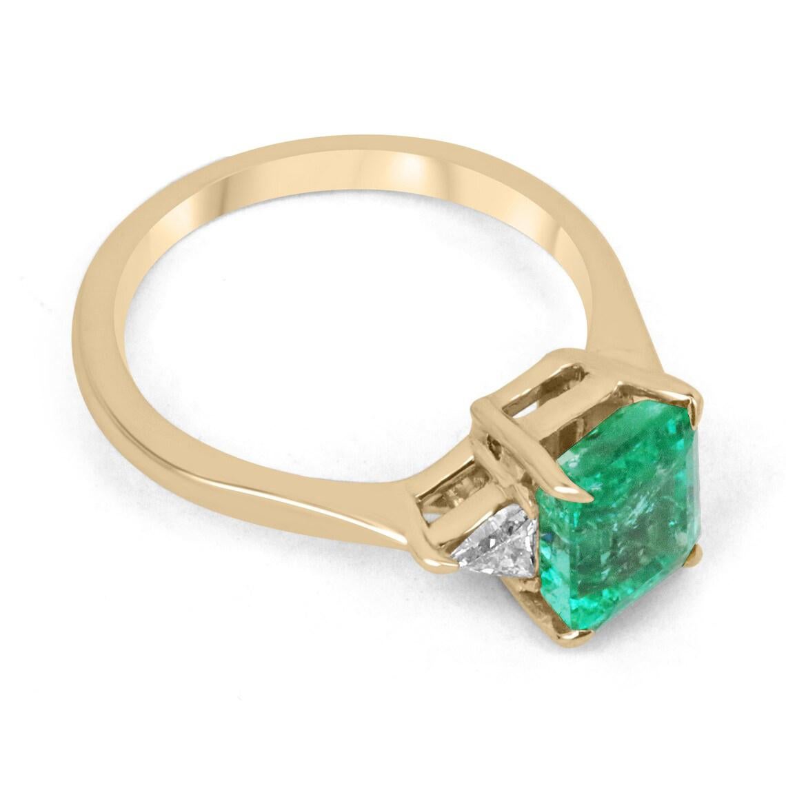 Un lussuoso anello a tre pietre con smeraldo e diamante. Questo magnifico pezzo presenta come pietra centrale uno straordinario smeraldo tagliato proveniente dallo Zambia. La gemma presenta un colore verde smeraldo scuro e desiderabile, con