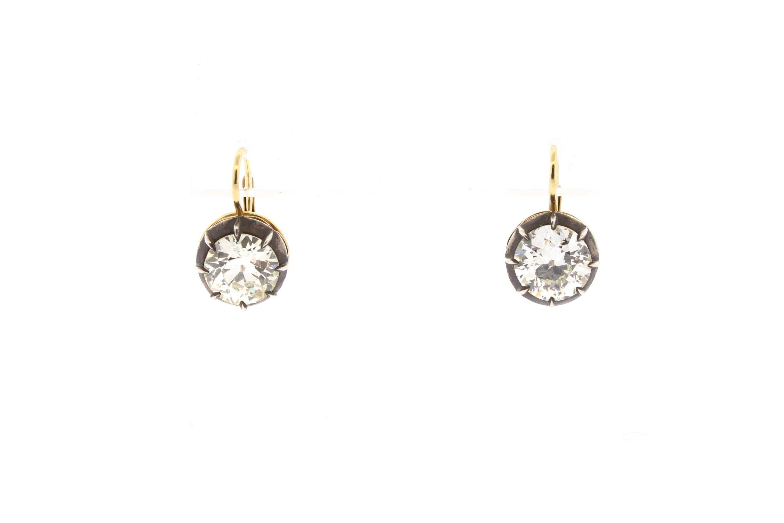 Single stone Old European cut diamond earrings weighing 2.46 ct and 2.55 ct set in silver topped gold collet settings. These earrings were made in our workshop in 18k gold and have an oxidized collet setting. The diamonds are antique, perfectly
