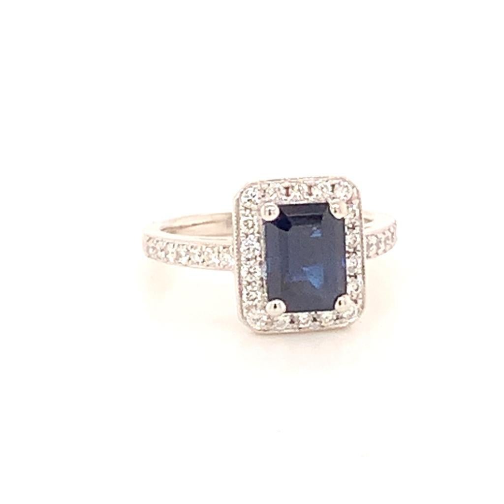 This flawlessly designed ring features a stunning 2.46 Carat Emerald Cut Blue Sapphire at its centre. The rich, dark hues of this invaluable gemstone are framed by glittering Round Brilliant Diamonds set in a diamond encrusted Platinum band. The