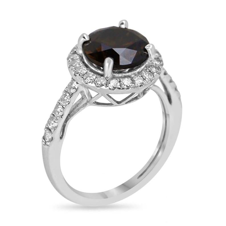 This exquisite diamond engagement ring showcases a mesmerizing 2.02 carat round cut fancy dark brown diamond with a hint of dark orange, radiating a captivating allure. With remarkable luster and SI1 clarity, the center gem captures attention. A