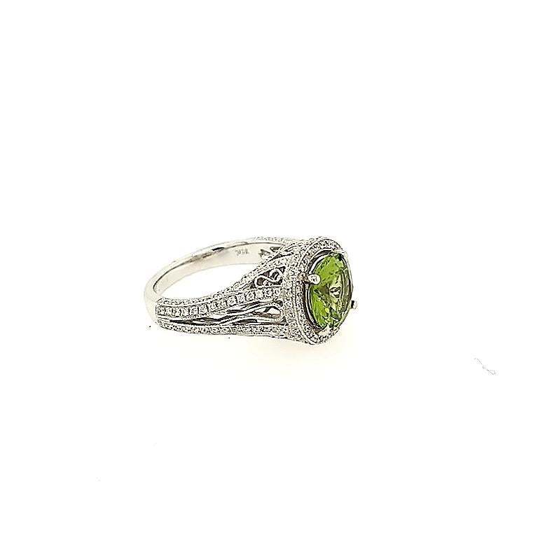 Crafted in 14k white gold featuring (1) round peridot weighing 2.48 carat and surrounded by one hundred and eighty seven round diamonds weighing approximately .74 carat total weight. The ring measures size. The perfect gift for those August