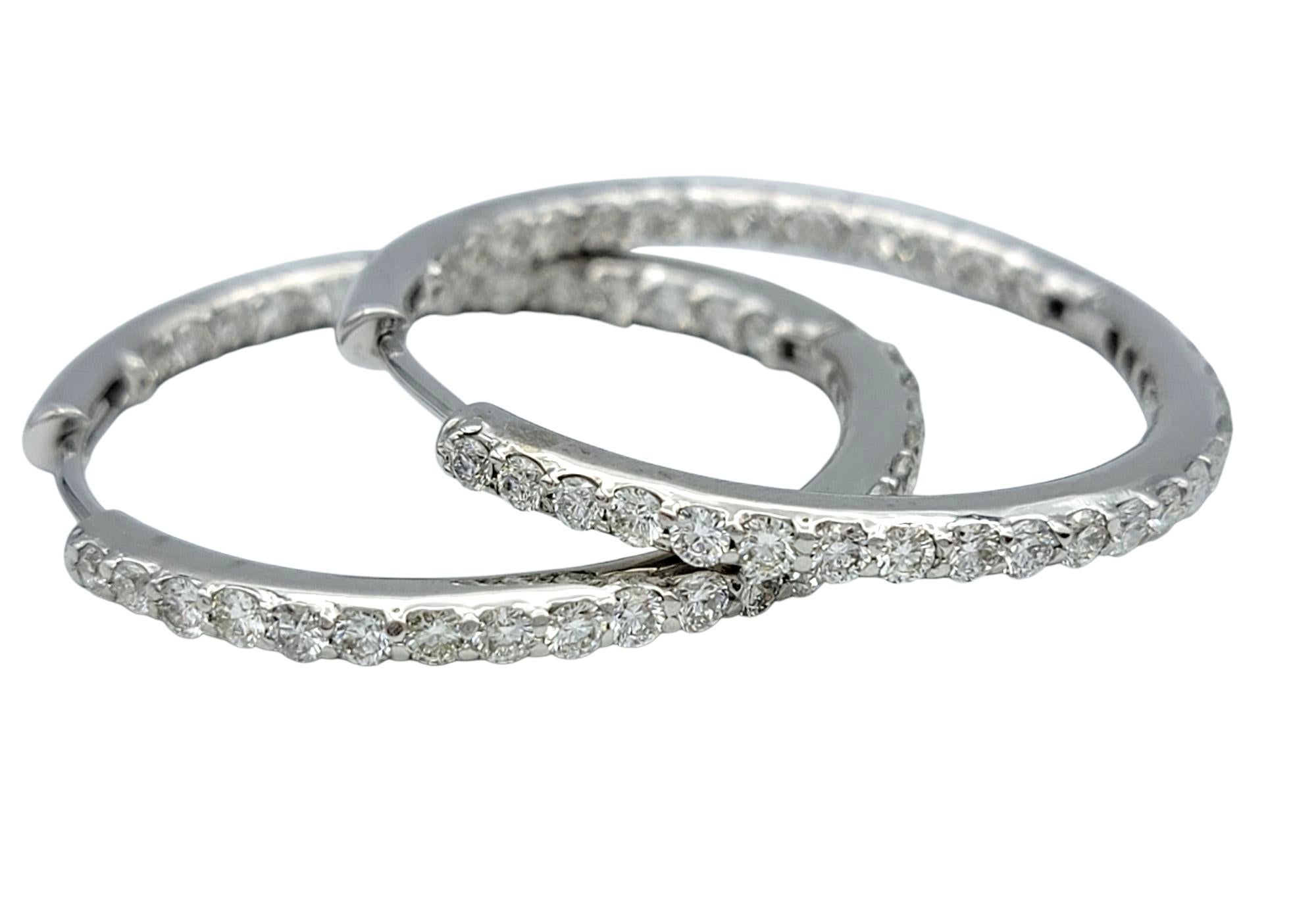 Elevate your everyday look with the timeless sparkle of these diamond hoop earrings. Crafted in radiant 14 karat white gold, each hoop is adorned with a continuous row of round cut diamonds that deliver brilliant shine from every angle. The clean,