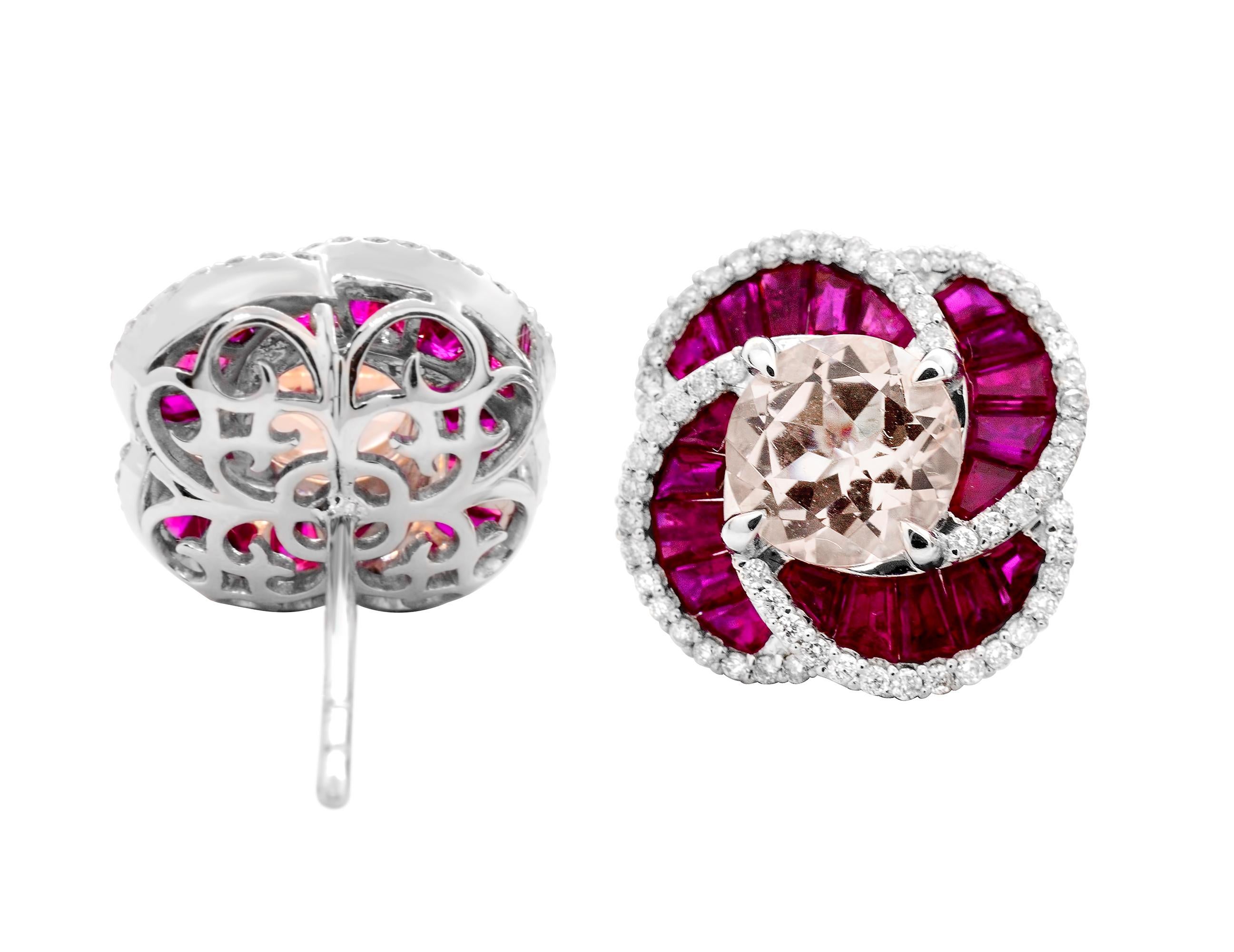 Contemporary flower motif stud earrings set in 14 Karat white gold.  
These center round morganites have a light pink color with the slightest splash of orange and are a substantial 7mm each. 
They are surrounded by the richest red ruby baguettes of
