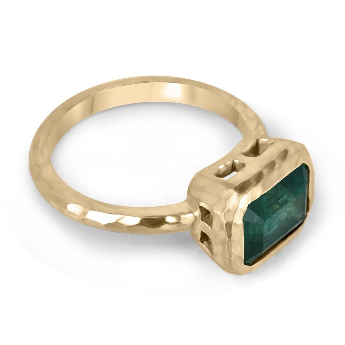 Displayed is a stunning East-to-West emerald solitaire engagement or right-hand ring in 14K yellow gold. This gorgeous solitaire ring carries a 2.48-carat emerald in a bezel setting. Fully faceted, this gemstone showcases excellent shine and