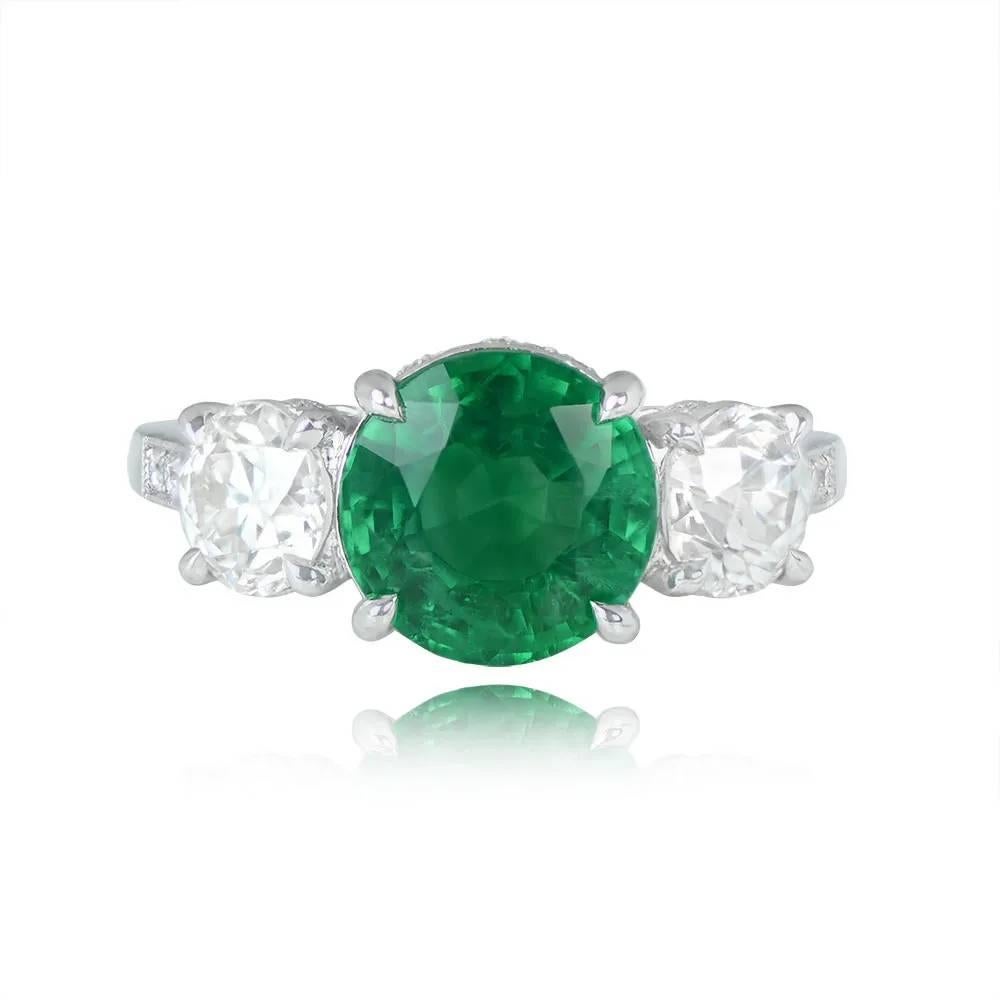A stunning three-stone ring showcasing a round natural green emerald of about 2.48 carats with excellent saturation. The center stone is complemented by two old European cut diamonds, totaling 1.29 carats (I color, VS2 clarity overall). Crafted in