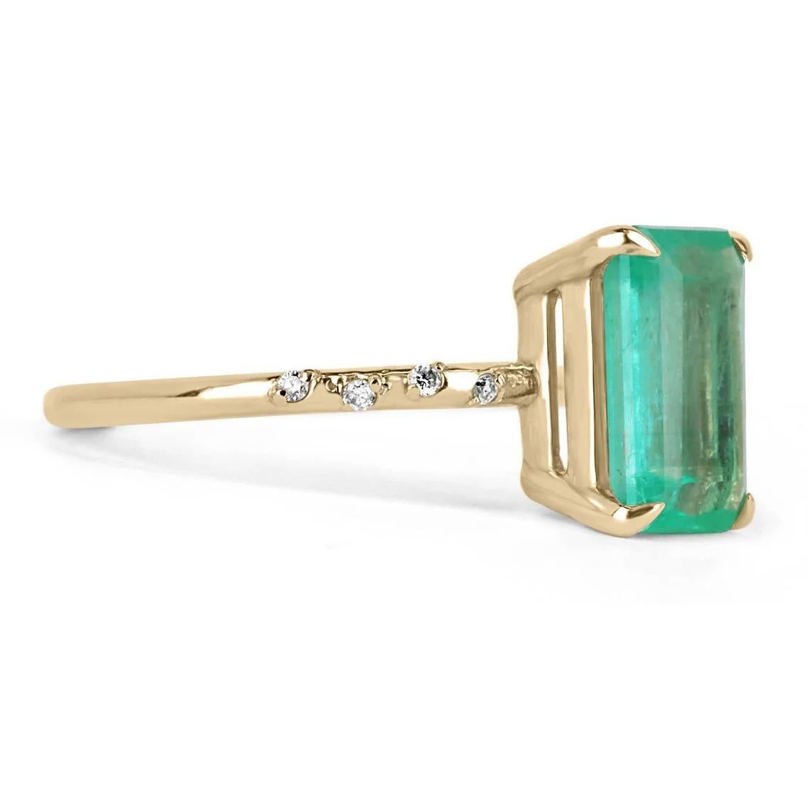 Displayed is a modern emerald and diamond solitaire engagement ring/right-hand ring in 14K yellow gold. This gorgeous solitaire ring carries a full 2.40-carat emerald in a four-prong setting. The emerald has very good clarity with minor flaws that