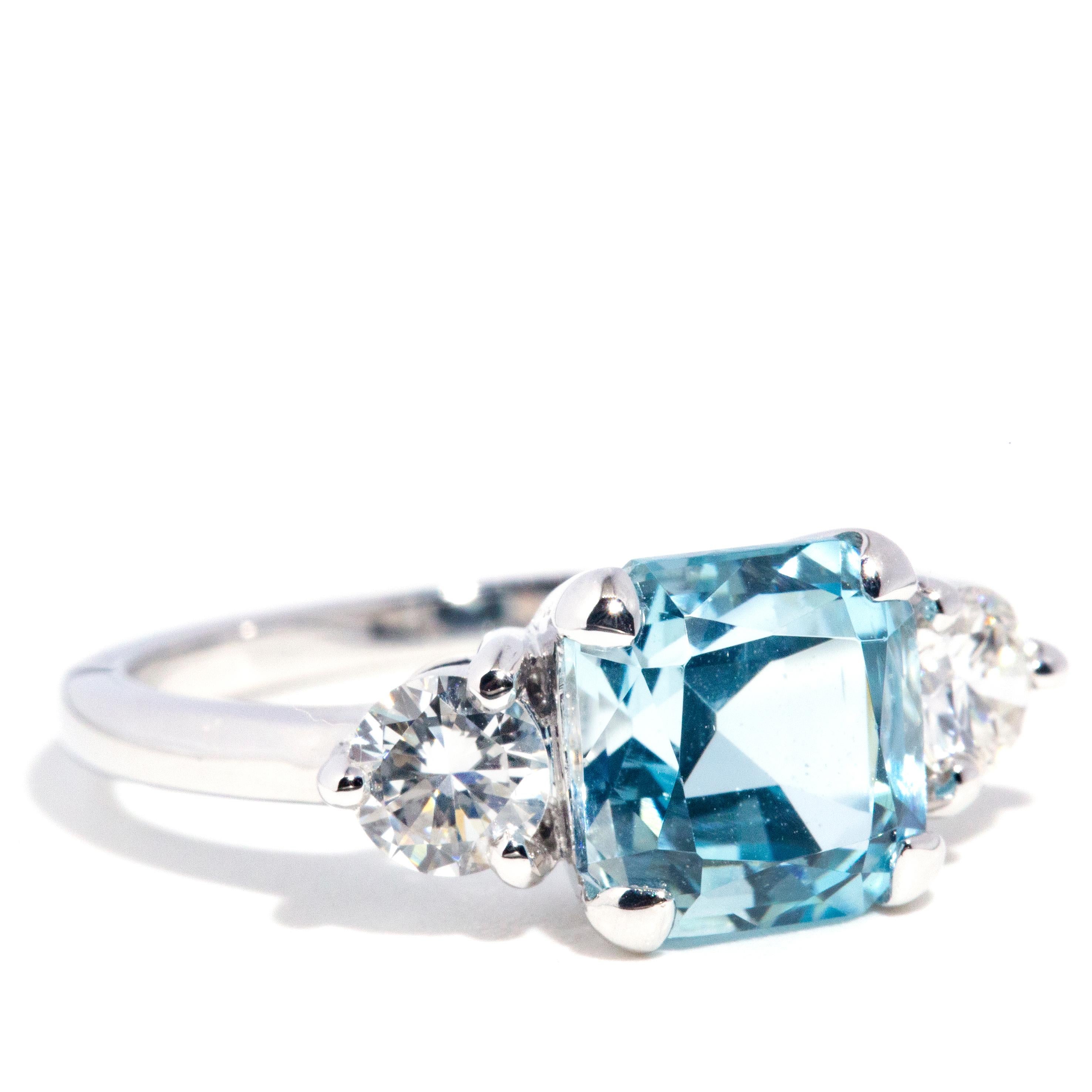 Exquisitely crafted in 18 carat white gold, this gorgeous three stone ring is a captivating show of light with a spectacular 2.42 carat bright blue aquamarine carefully set between a stunning 0.58 carats of certified round brilliant cut diamonds. We