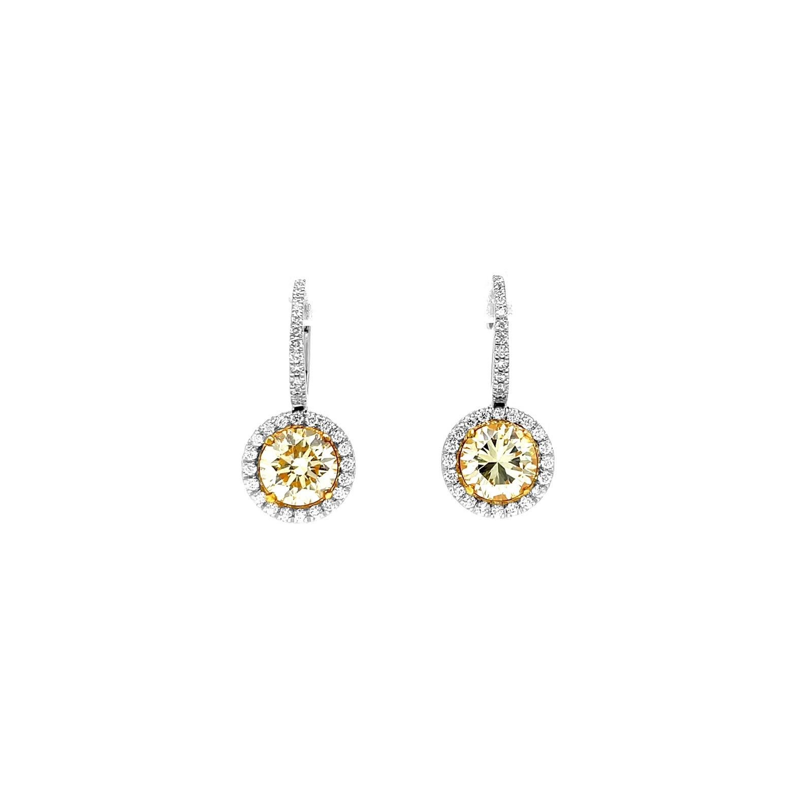 Elégantes et intemporelles, ces exquises boucles d'oreilles en diamant jaune clair certifié GIA présentent deux diamants jaunes ronds de taille brillant parfaitement assortis, pesant au total 2,17 carats (1,08 ct et 1,09 ct). Chaque diamant brille