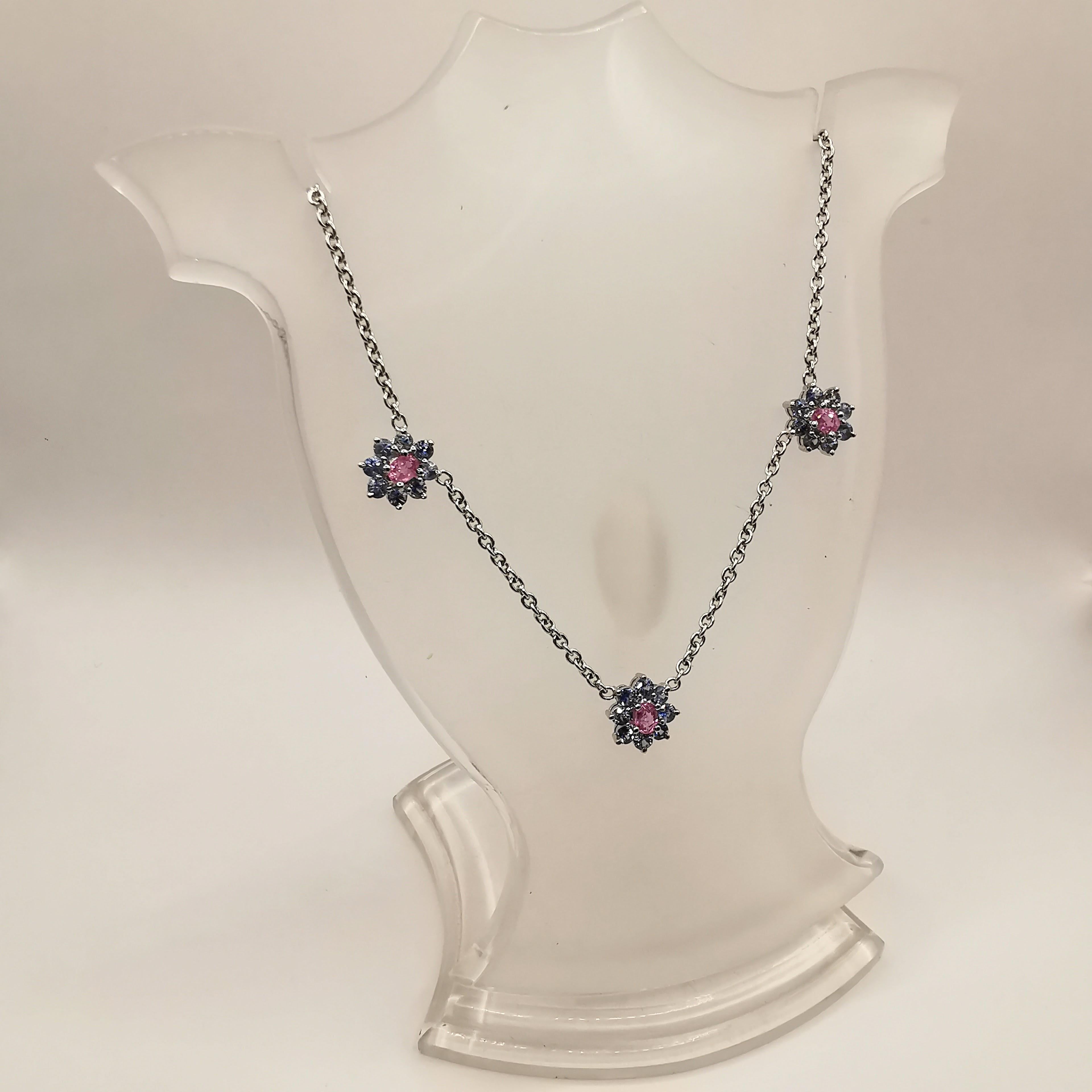 Introducing our beautiful 2.49 Carat Pink & Blue Sapphire Flower Necklace, crafted in 18K white gold. This necklace features a stunning design, made up of three flowers, each one with an oval cut pink sapphire in the center, surrounded by a halo of