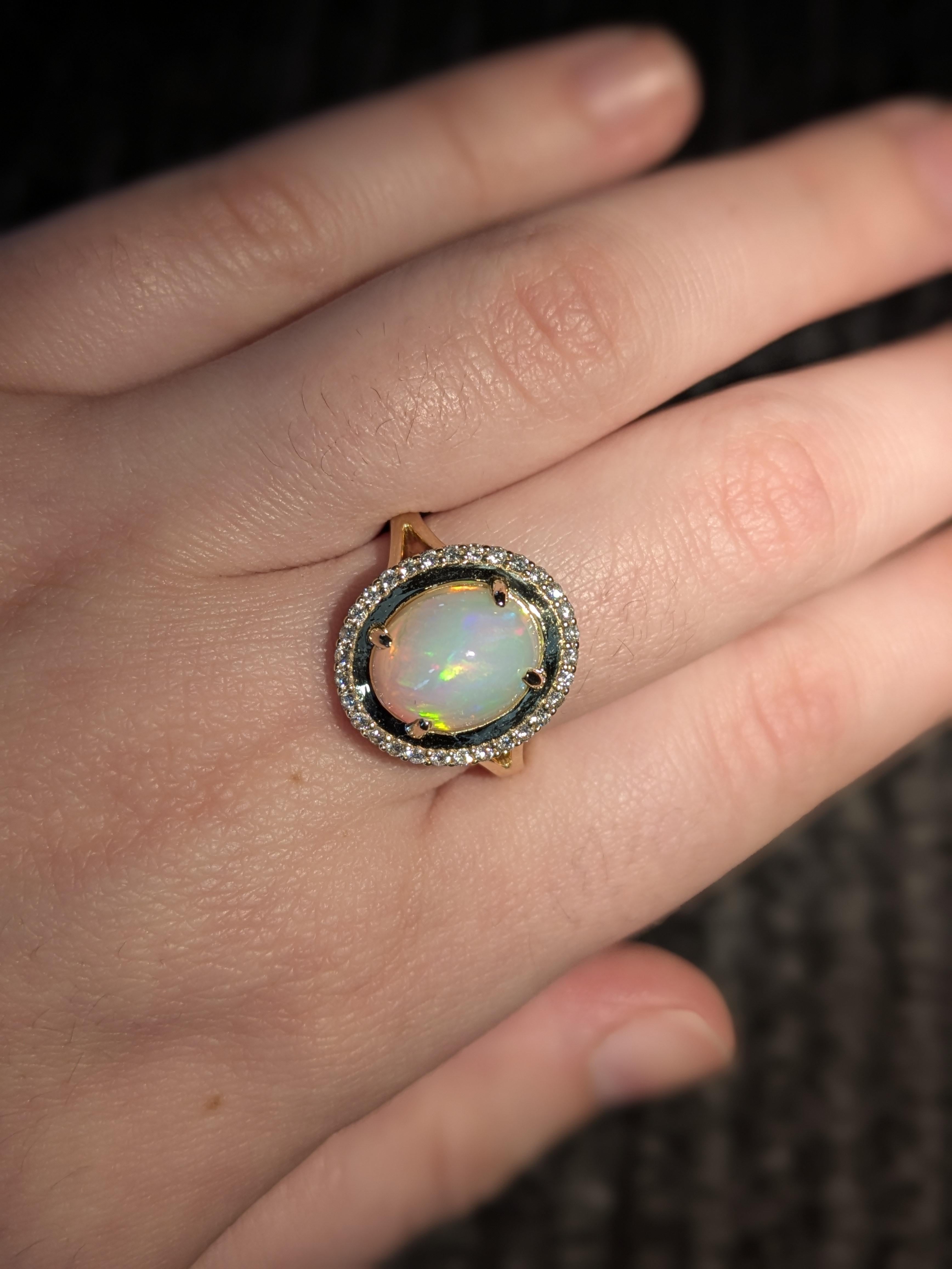 Ein 2,4-karätiger äthiopischer Opalring, gefasst in massivem 14-karätigem Gold, mit natürlichen Diamanten als Akzentsteinen, die einen 11 × 9 mm großen ovalen Opal einrahmen - ein lebhaftes, elegantes Stück, das feurige Farbspiele mit klassischer