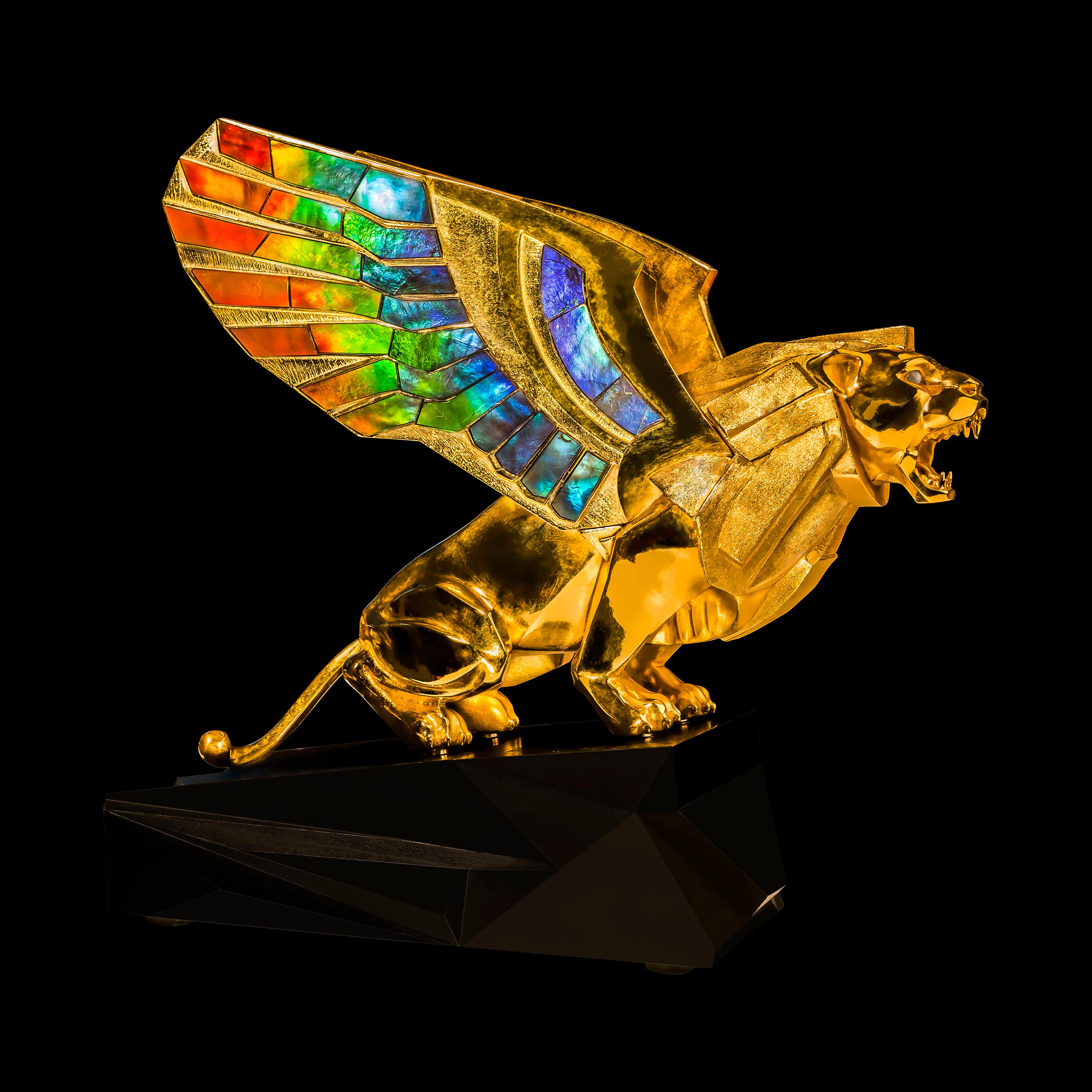 Golden gryphon sculpture in 24K gold plated sterling silver, with wings set with AAA grade ammolite, chrysoberyl cat's eye set upon an oxidized bronze pedestal.

The sculpture depicts a mighty Gryphon crouching in tension is prepared to jump. Its