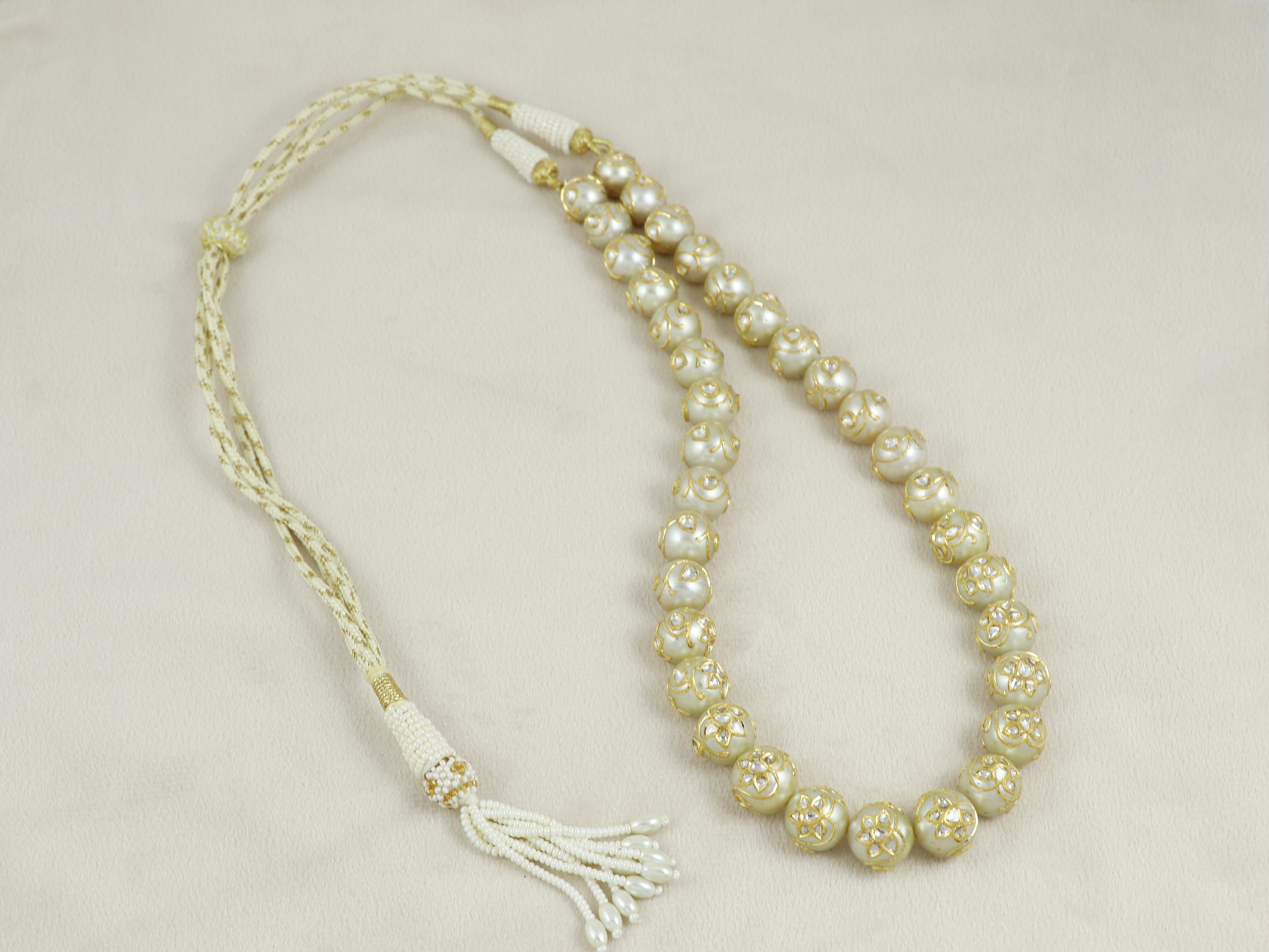 Una collezione di 35 perle del mare del sud infilate insieme per formare una collana a linea singola, con ogni perla incastonata con polacchi di diamanti e oro 24 carati.

Ogni perla viene incisa con il disegno di un fiore e di un petalo con una