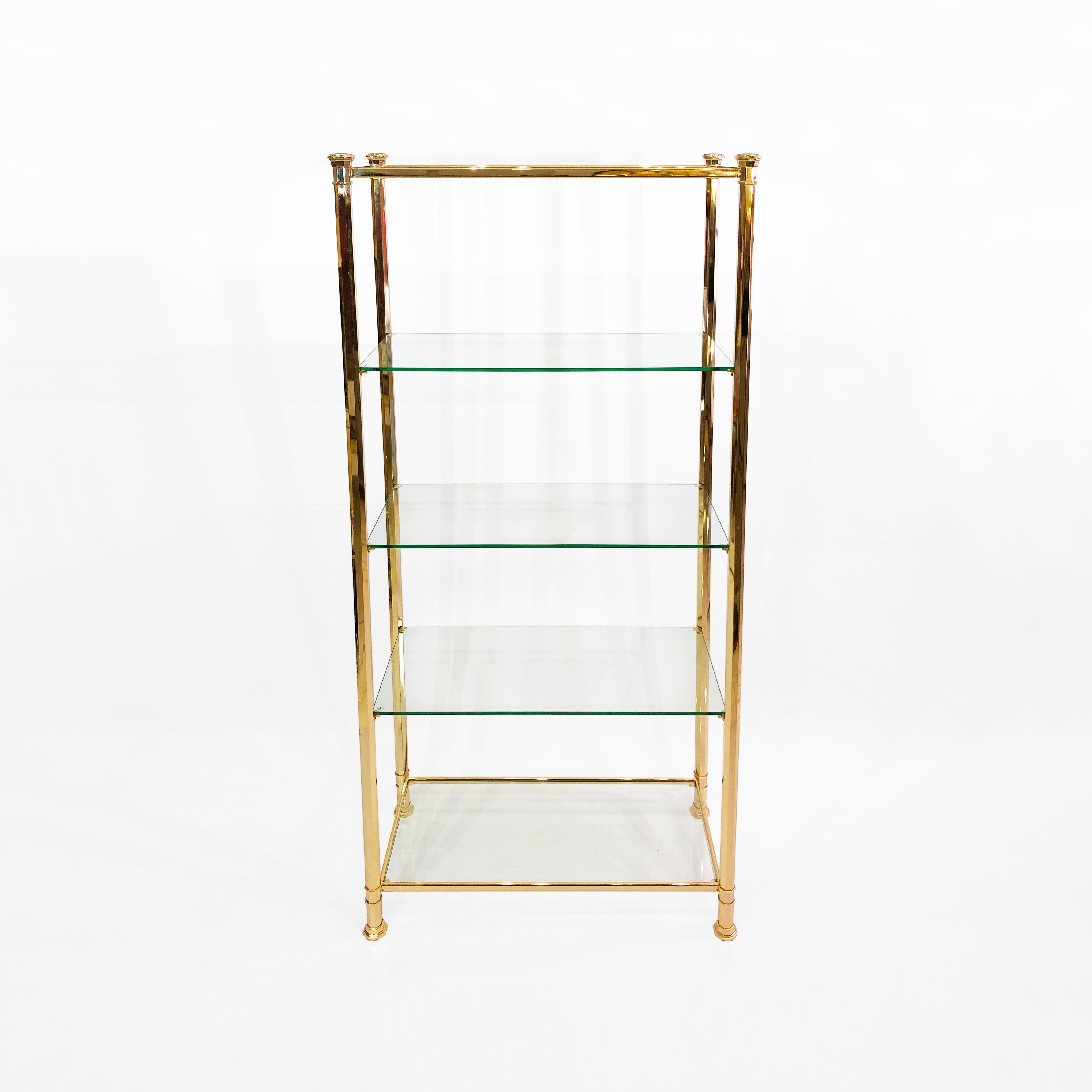 Questa alta étagère, realizzata in un'elegante forma poligonale placcata in oro 24k su ottone da Kesterport, è un eccellente esempio dell'opulenza Hollywood Regency degli anni '70. Una struttura in ottone con dettagli angolari regali sostiene cinque