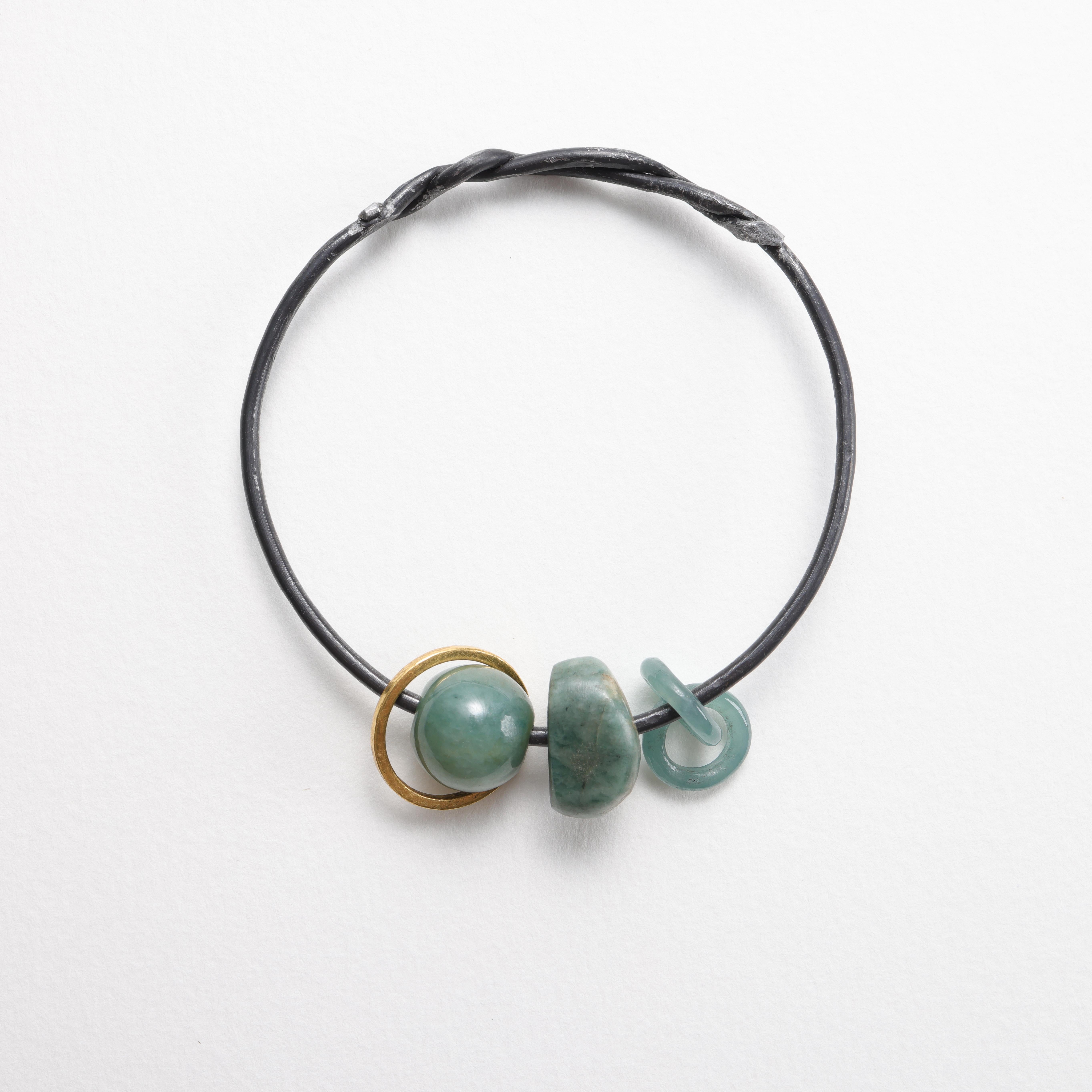 I created this bangle with heavy gauge Ohio steel that I hand-work into shape. This bangle features one primitive-cut bluish-green natural and untreated jadeite bead from Guatemala, a teal green untreated jadeite bead from Burma (Myanmar), a