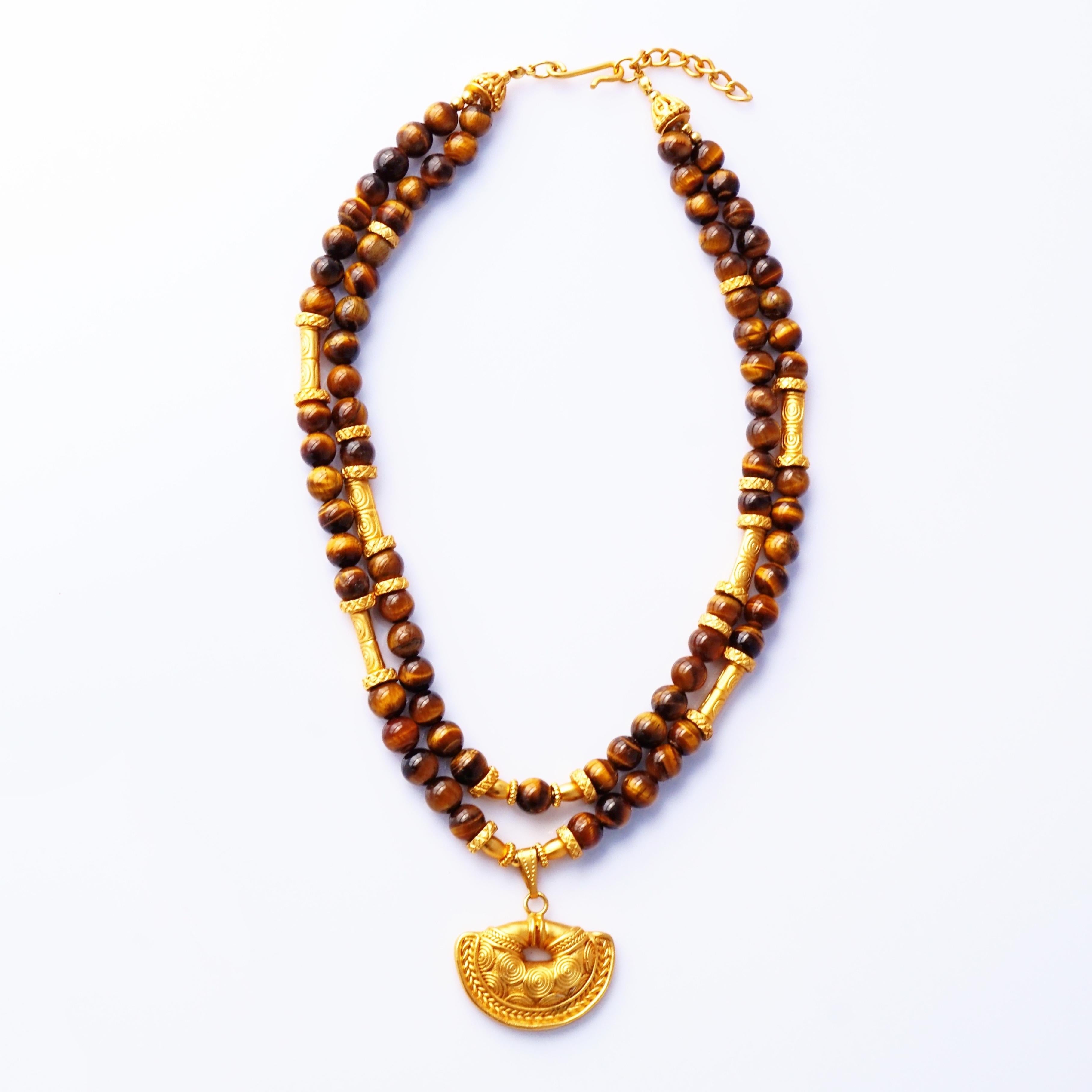 Este collar de los años 70 de la lujosa casa colombiana Cano Jewelry es una fascinante declaración que canaliza el antiguo arte inca a través de la opulencia moderna. Dos ricas hileras de cuentas de ojo de tigre brillan con iridiscencias terrosas,