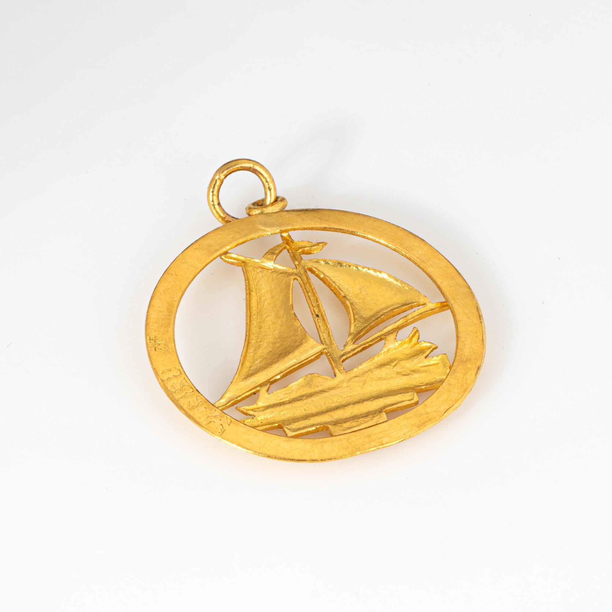 Finely detailed sailing boat pendant crafted in 24k yellow gold (circa 1980s).   

The pendant measures 28mm diameter (1.10 inches) and features a sailing boat with sails in full flight. The bale measures 4mm wide and can accommodate a thin to