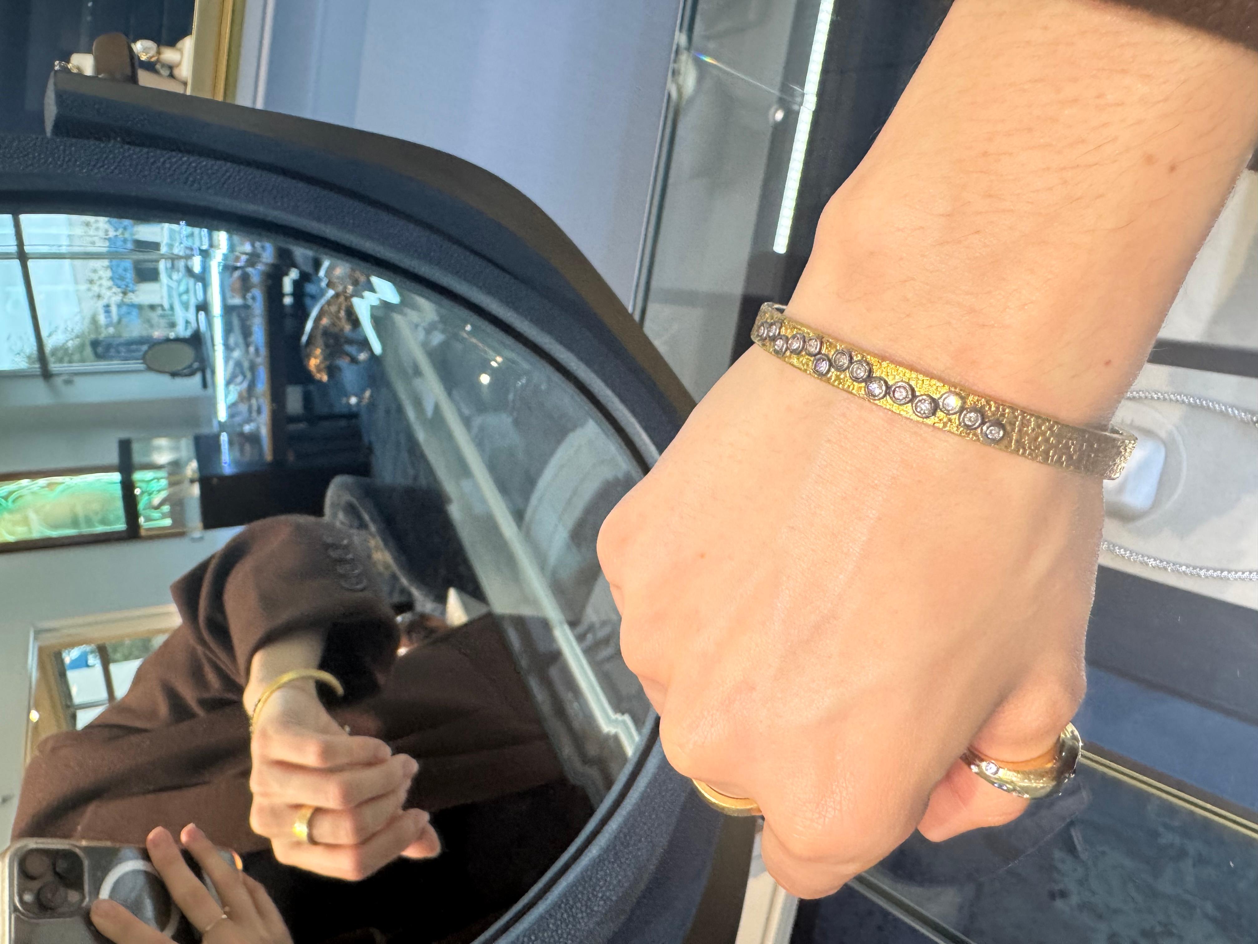 This striking 24k yellow gold and silver cuff bracelet combines bold luxury with timeless craftsmanship. The bracelet features a hammered finish texture, giving it a unique, handcrafted look that catches the light with every movement. The warm, rich