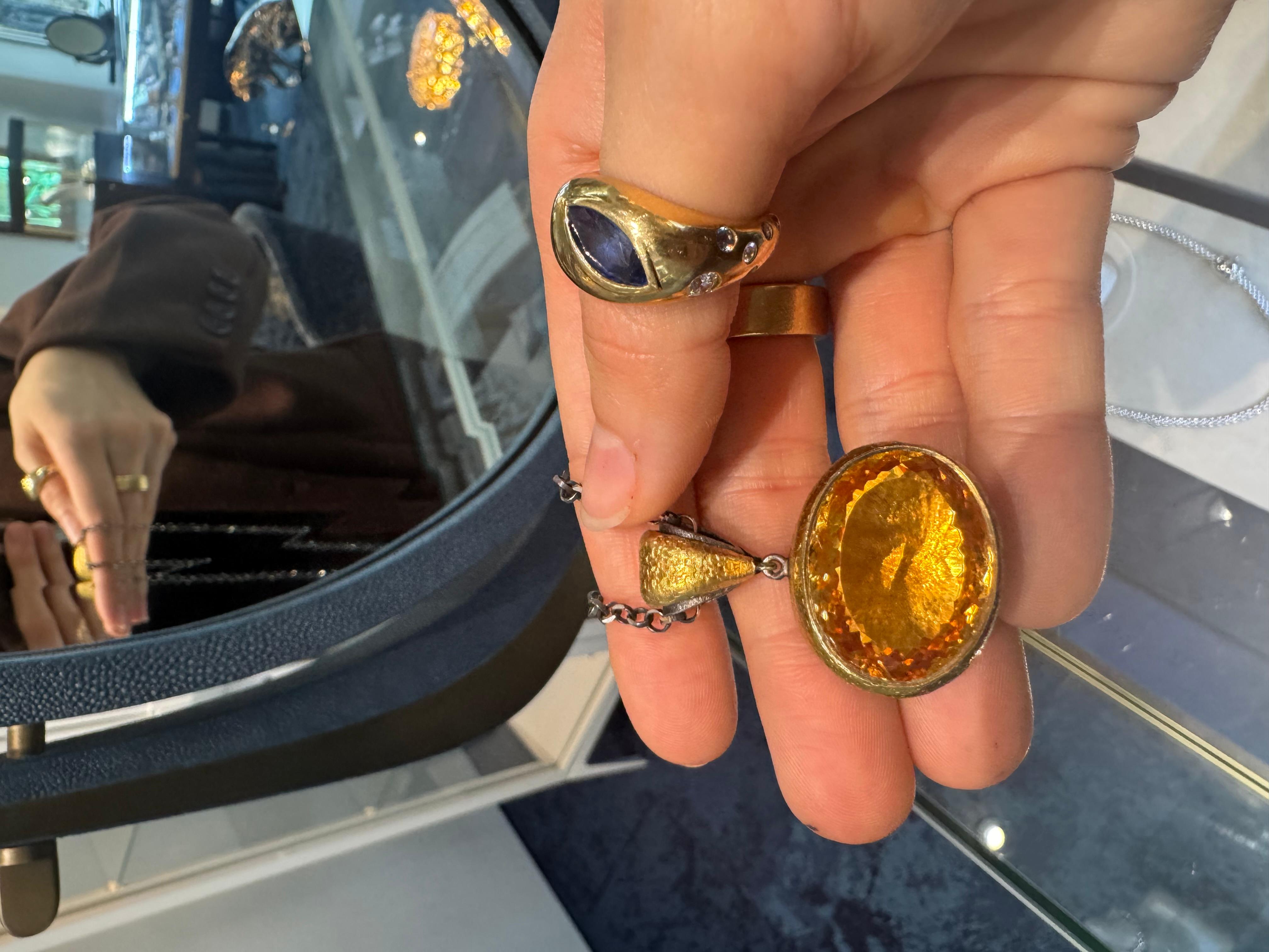 This elegant necklace features a sleek sterling silver link chain paired with a stunning 24k yellow gold citrine pendant. The pendant itself is crafted with a hammered finish, adding texture and depth to its luxurious 24k yellow gold setting. The