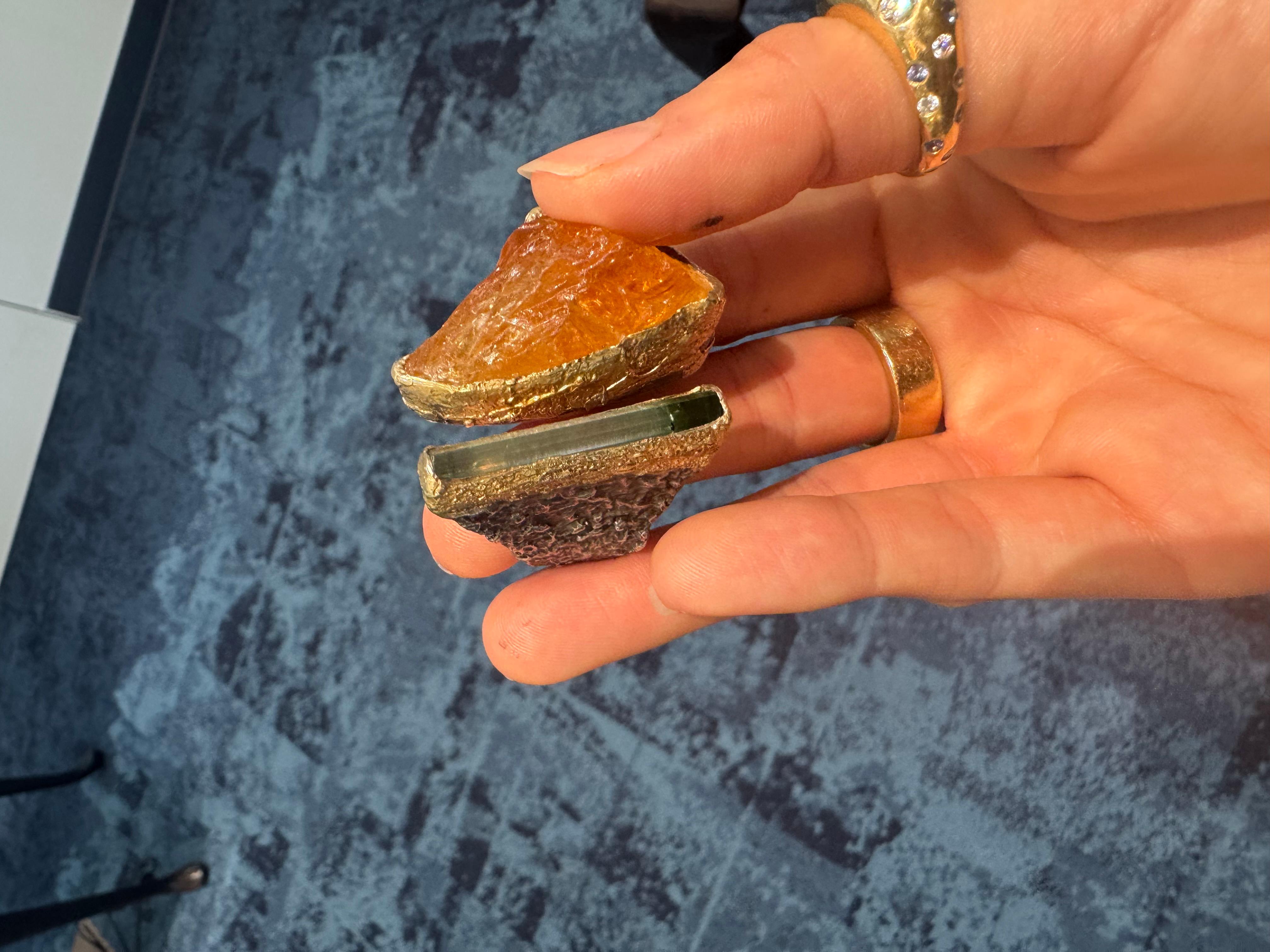 This captivating 24k yellow gold and sterling silver ring blends the beauty of raw gemstones with a Mediterranean-inspired design. Featuring two stunning raw gemstones—citrine and tourmaline—each stone is bezel-set in rich 24k yellow gold. The warm