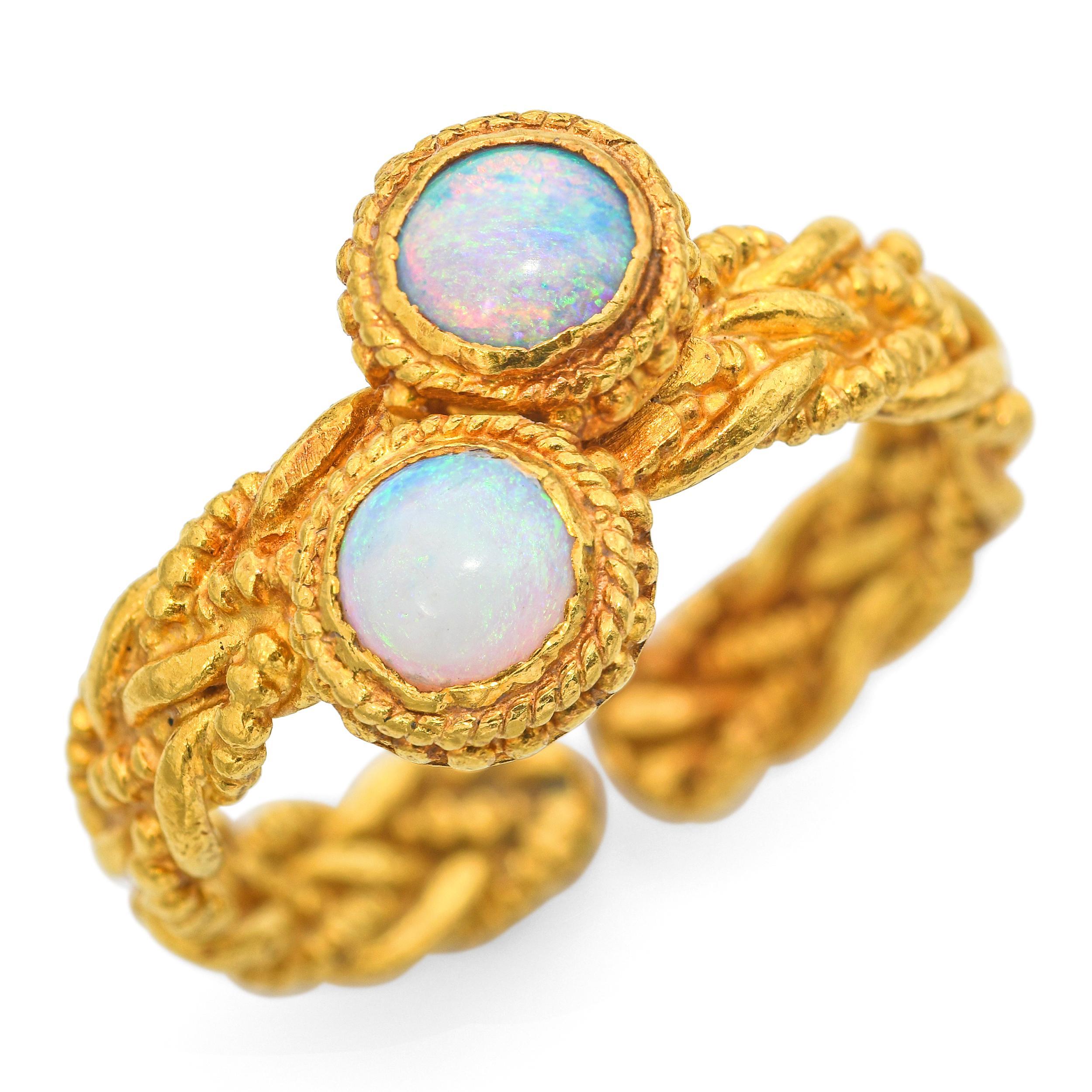 Questo anello unico ed elegante è realizzato in puro oro giallo 24 carati e presenta un romantico design Toi/One con due cabochon opali rotondi abbinati. Ogni opale mostra vibranti lampi di colore, blu, verdi e arancioni infuocati, che si muovono