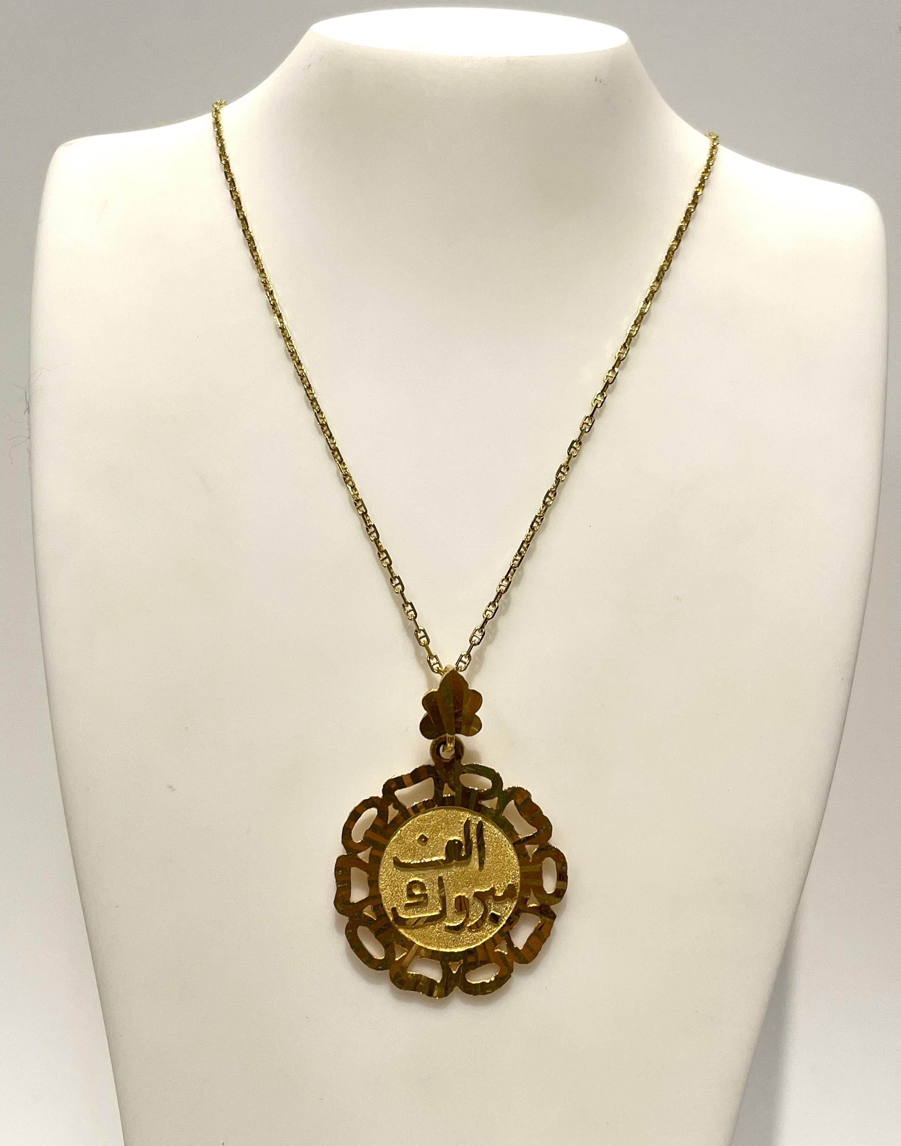 Bellissimo ciondolo decorativo a forma di disco con scritta araba.
Il ciondolo è un disco rotondo e smerlato in oro giallo 24 carati con dettagli ornamentali.  
Le lettere arabe dicono 