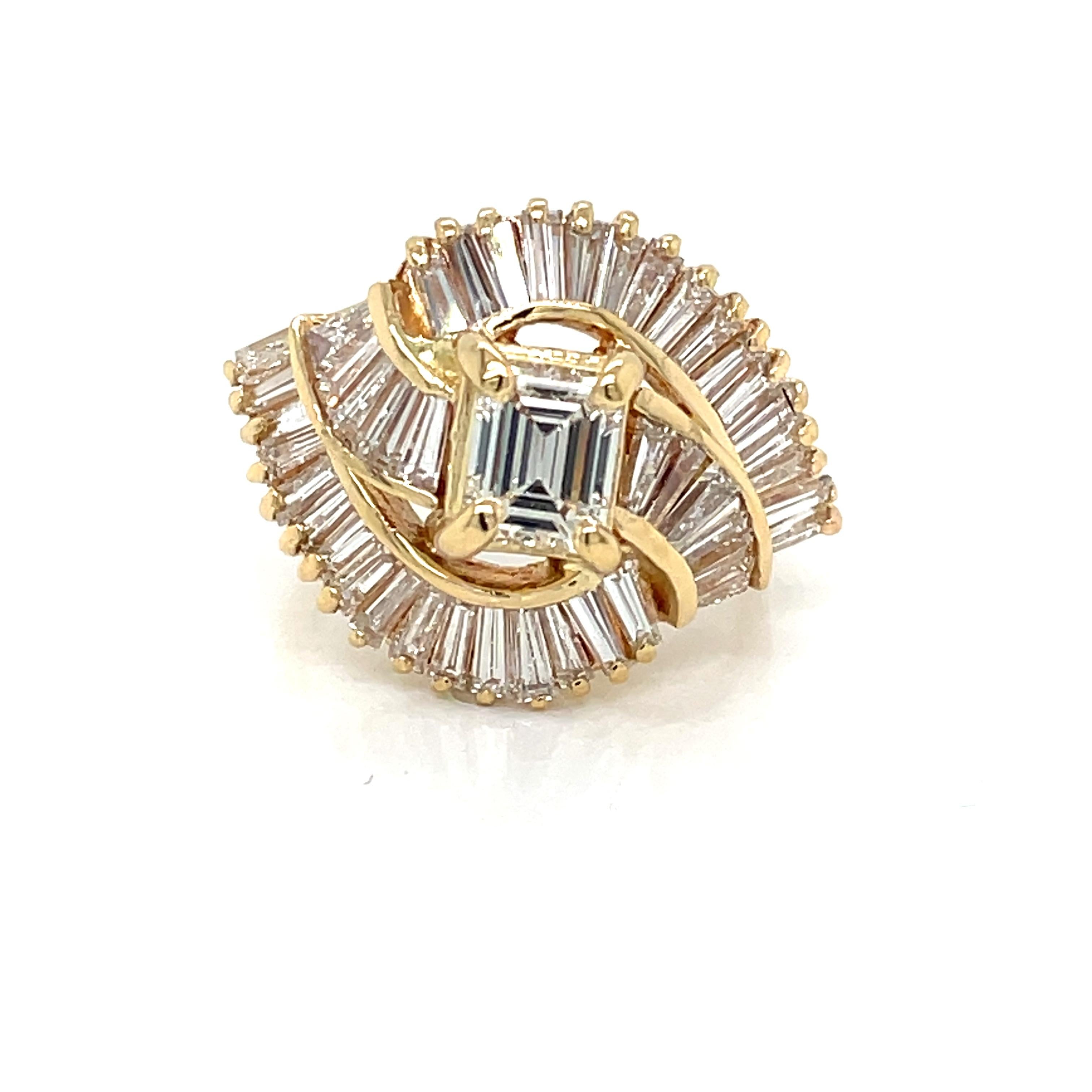 Presenting over 2.5 carats total weight, this stunning cocktail ring dazzles with three distinctive multi-dimensional flairs of sparkling emerald cut diamonds set in bright 18 karat yellow gold. Over fifty diamond baguettes create the stylish halo