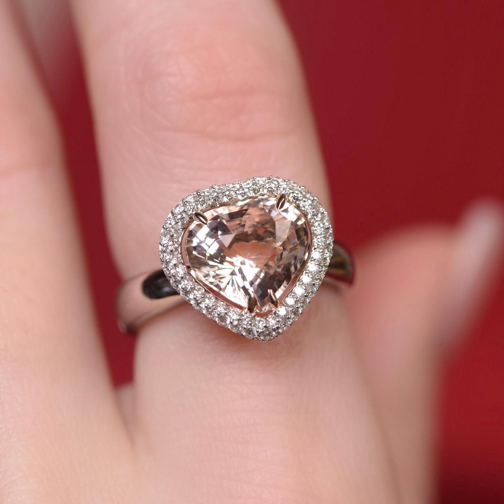 We love to work with natural pink stones such as the morganite in this ring.
Heart shape makes the appearance of this morganite very romantic and delicate.
Its peach pink hue looks gorgeous in a diamonds pave frame. 
We decided to make this ring in