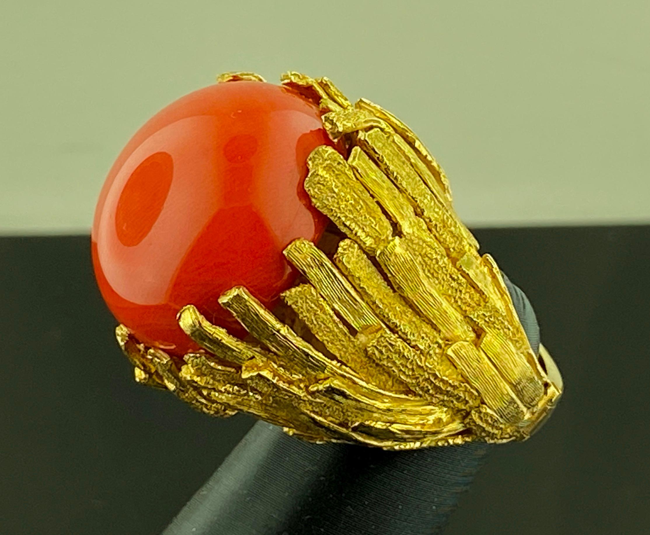 In kunstvollem 18-karätigem Gelbgold mit einem Gewicht von 46 Gramm ist eine rote Oxblood-Koralle im 25-Millimeter-Cabochon-Schliff gefasst.  Die Ringgröße ist 3,5 mit einem Schaft, der sich öffnet.