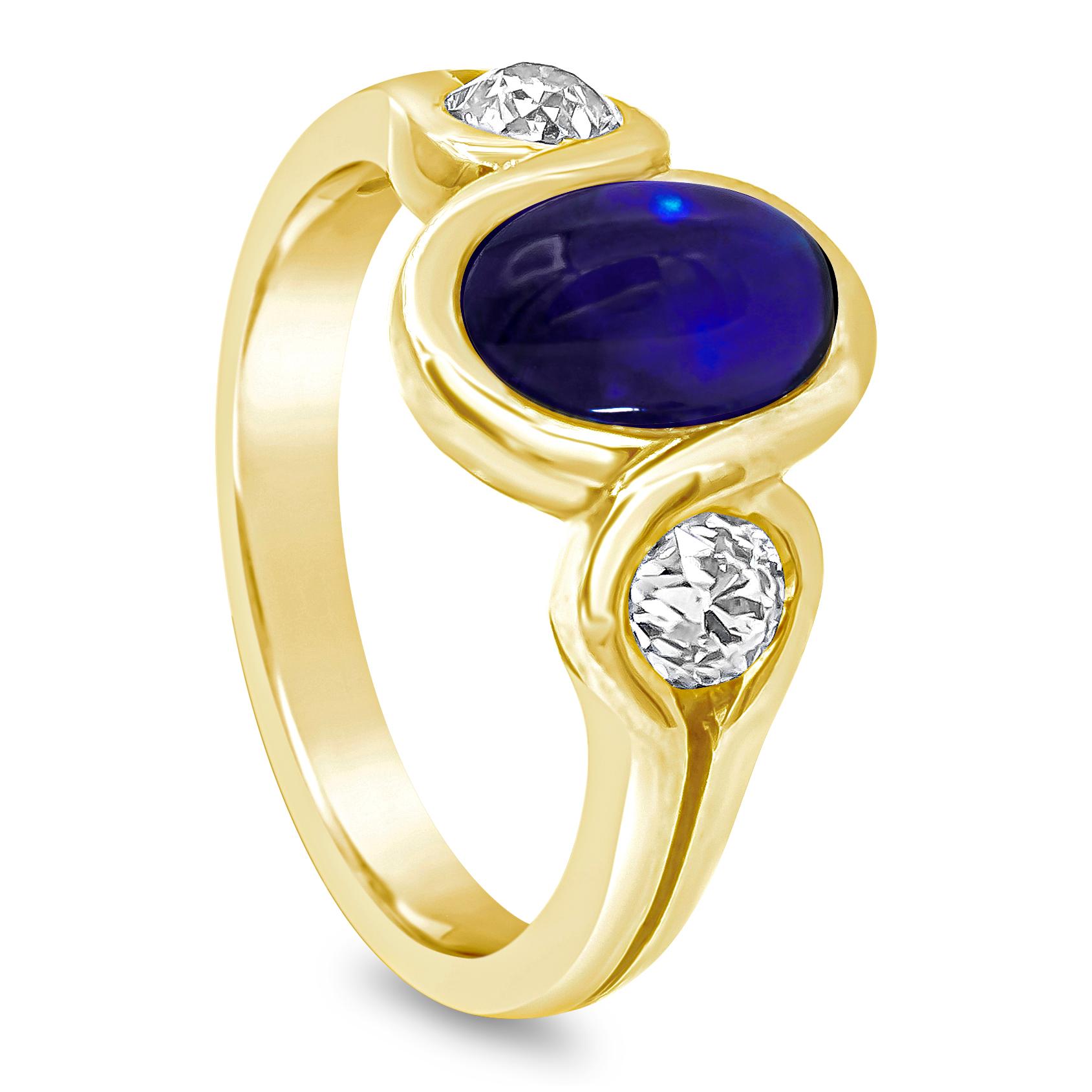 A appealing gemstone fashion ring showcasing a 2.50 carat oval shape blue sapphire cabochon in the center and an old european cut diamond on each side weighing 0.80 carats total. Set in an integrated bezel, Made in 18K Yellow Gold, Size 7.5 US

