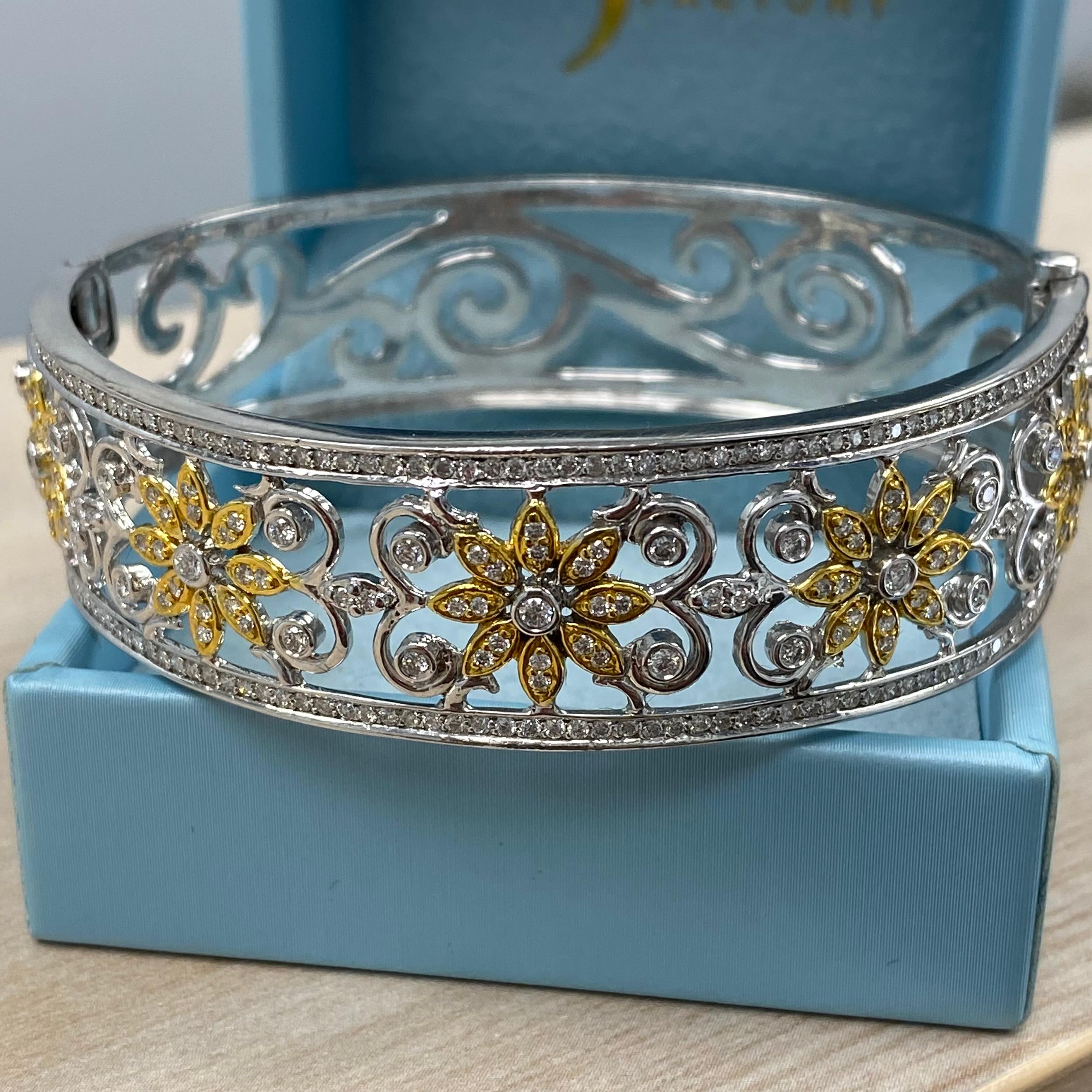 This stunning diamond bangle bracelet is crafted from 30.2 grams of 14k white gold, featuring delicate yellow gold flower accents nestled between two rows of sparkling diamonds. It boasts a total of 2.50 carats of colorless G/H color, VS/SI clarity