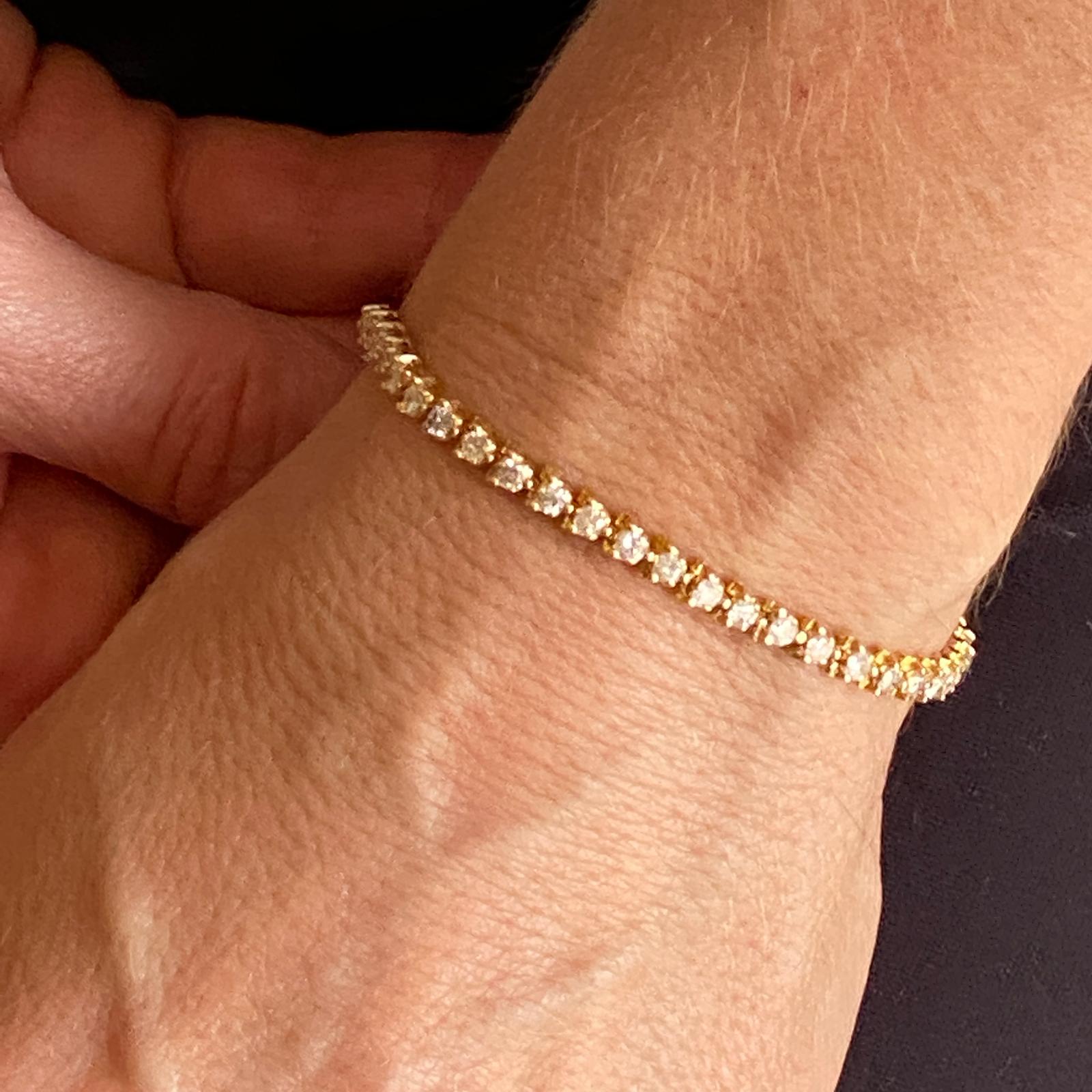 Popular diamond tennis bracelet fashioned in 14 karat yellow gold. The 51 round brilliant cut diamonds weigh approximately 2.50 carat total weight, and are graded G-H color and SI clarity. The bracelet measures 7 inches in length, and features a