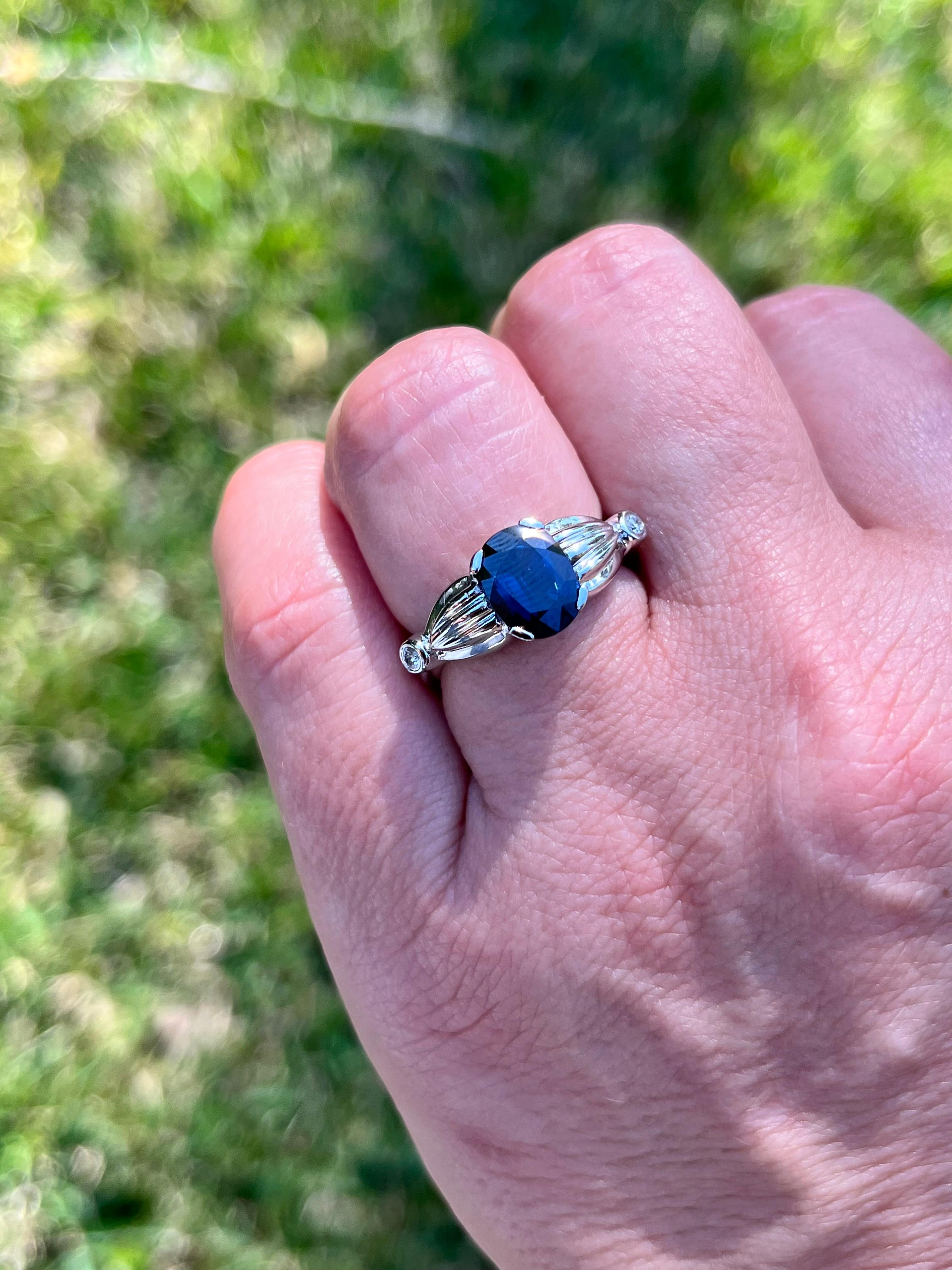 2.50 carat oval cut Blue Sapphire set with 2 diamond accents in a 14k white gold ring. The ring is made with an open split shank that securely wraps around the finger for a comfortable fit. Double Rhodium plated for a long-lasting shine. Waterproof,