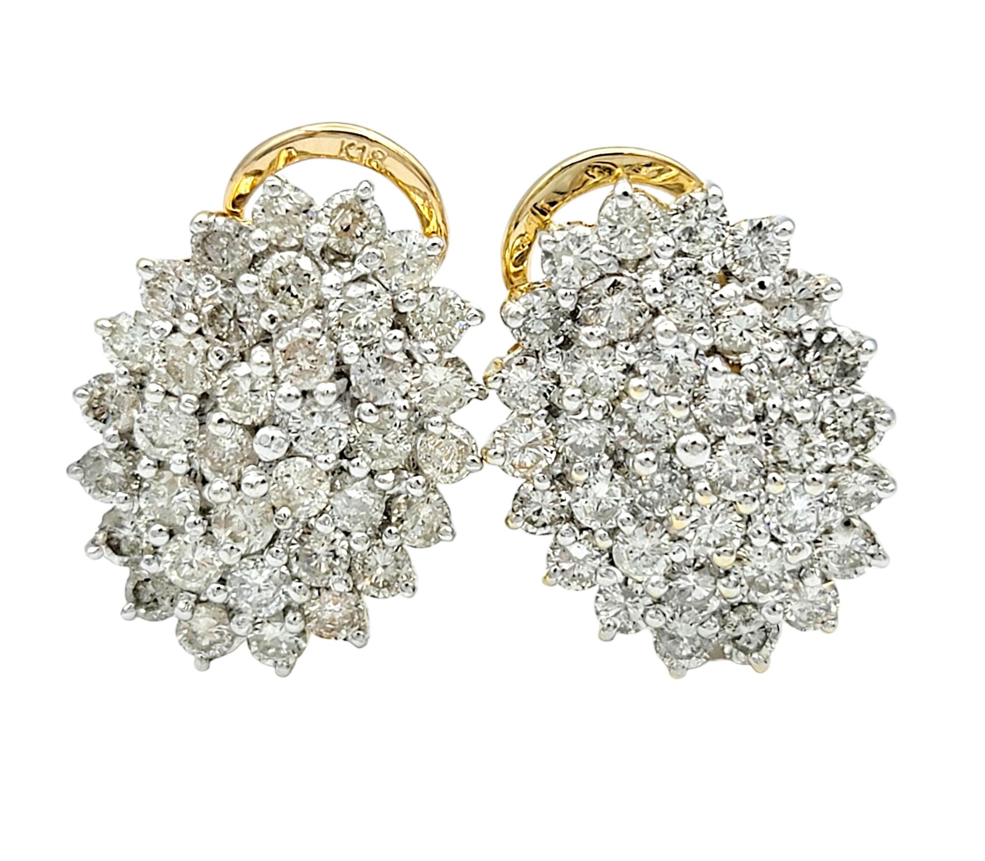 This gorgeous pair of earrings, set in lustrous 18 karat yellow gold, showcases a classic and elegant design. Each earring features a set of round diamonds arranged in an oval-shaped cluster, creating a harmonious and timeless composition. The round