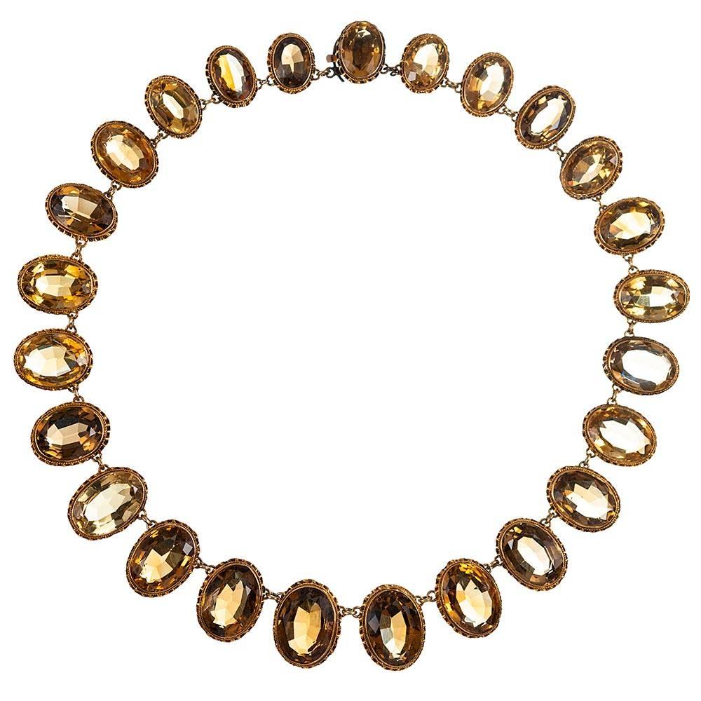 Twenty-five faceted oval citrine are gently graduated in size and each nestled in an ornate bezel setting. The stones weigh approximately 250 carats in total. The piece is made of 15k yellow gold and measures 16.5 inches long. Citrine exhibits a