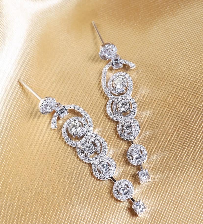 Boucles d'oreilles exquises en diamants, au design moderne, au style glamour et raffiné.
Les boucles d'oreilles sont en or 18 carats et contiennent des diamants brillants de 2,50 carats, de forme ronde et brillante, de couleur F et de pureté VS,