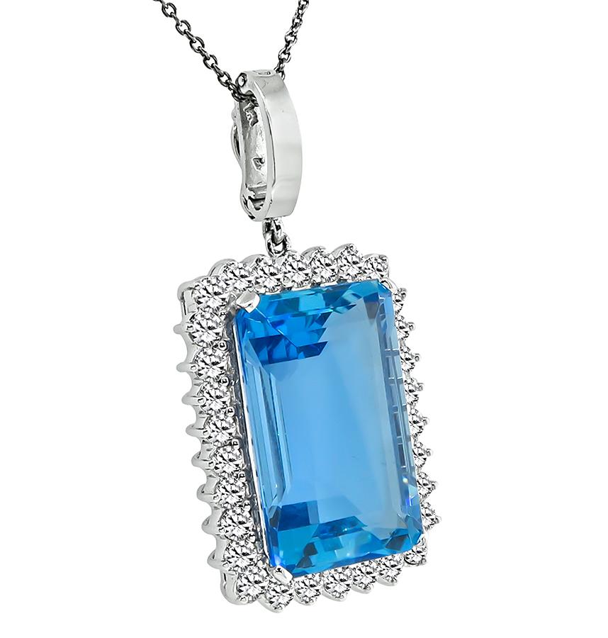 This is a beautiful 14k white gold pendant. The pendant is centered with a lovely emerald cut aquamarine that weighs approximately 25.00ct. The center stone is accentuated by sparkling round cut diamonds that weigh approximately 2.40ct. The color of