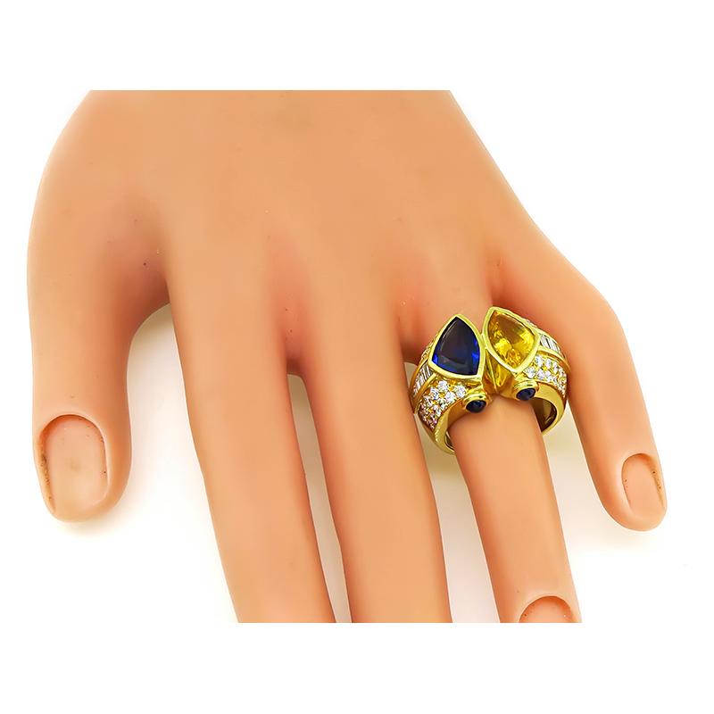 This is a charming 18k yellow gold ring. The ring is centered with lovely trilliant cut blue and yellow sapphires that weigh approximately 2.50ct. The sapphires are accentuated by sparkling round and baguette cut diamonds that weigh approximately