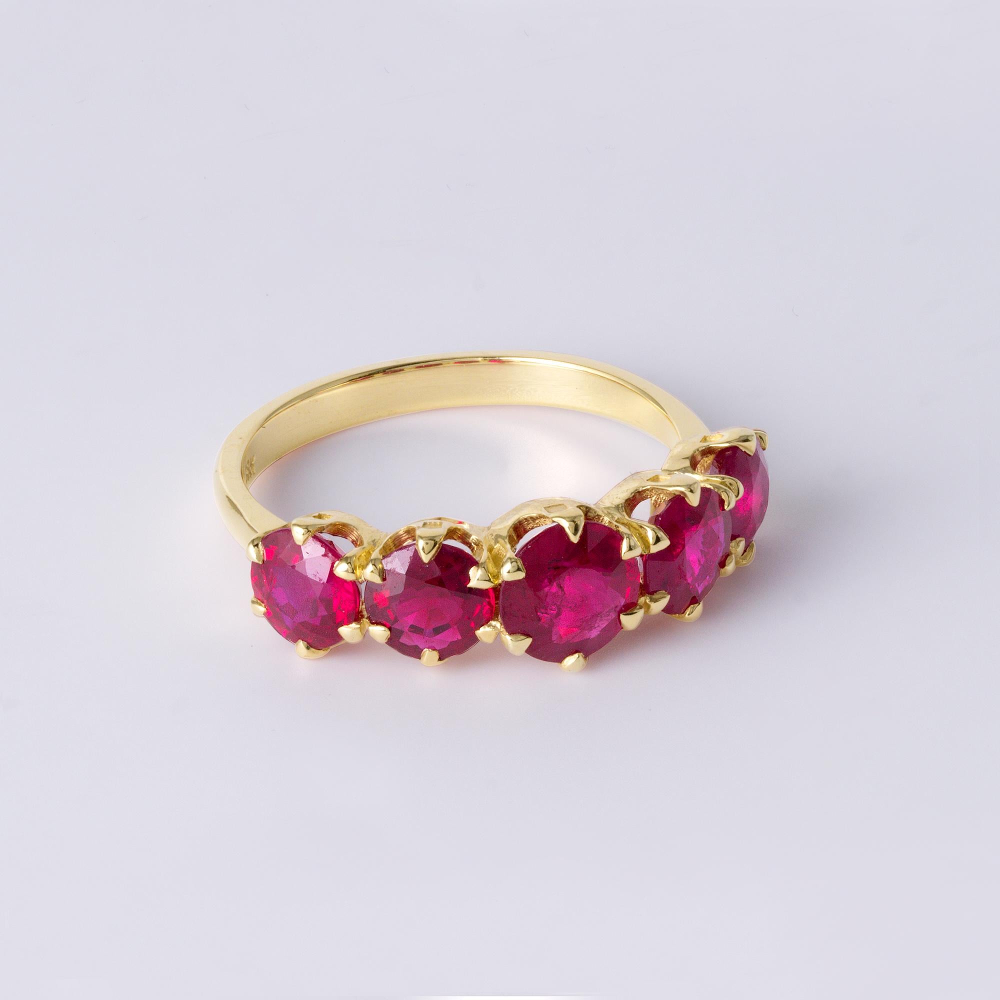 Questo squisito anello vintage con cinque pietre di rubino mette in mostra un'ardente e sofisticata esposizione di rubini naturali rotondi con taglio a brillante, rinomati per la loro origine e il loro colore eccezionale. Provenienti dalla Birmania