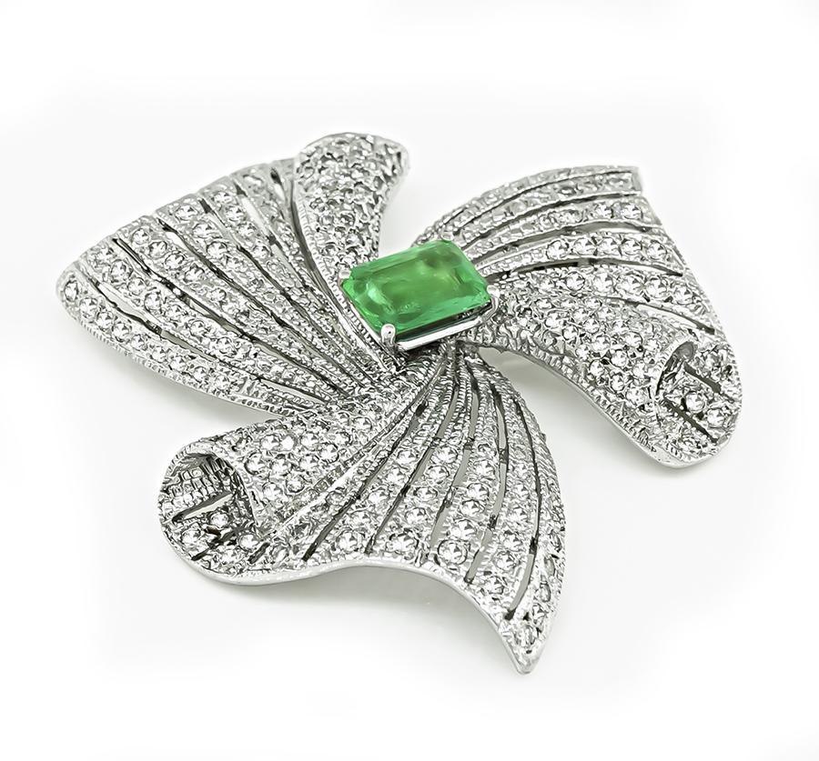 This is an elegant 14k white gold pin. The pin is centered with lovely emerald cut Colombian emerald that weighs approximately 2.50ct. The emerald is accentuated by sparkling round cut diamonds that weigh approximately 6.00ct. The color of these