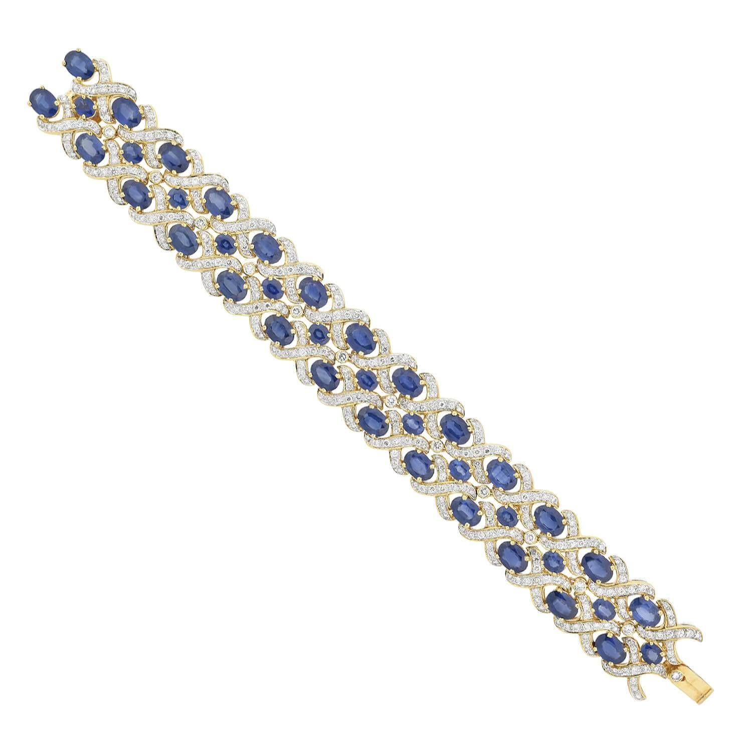 A Red Carpet worthy gemstone encrusted bracelet from the 1960s era! This exquisite piece is crafted in 18kt yellow gold and features a wide, flexible surface of diamond and sapphire encrusted links, which interlock to form a dramatic design. Each
