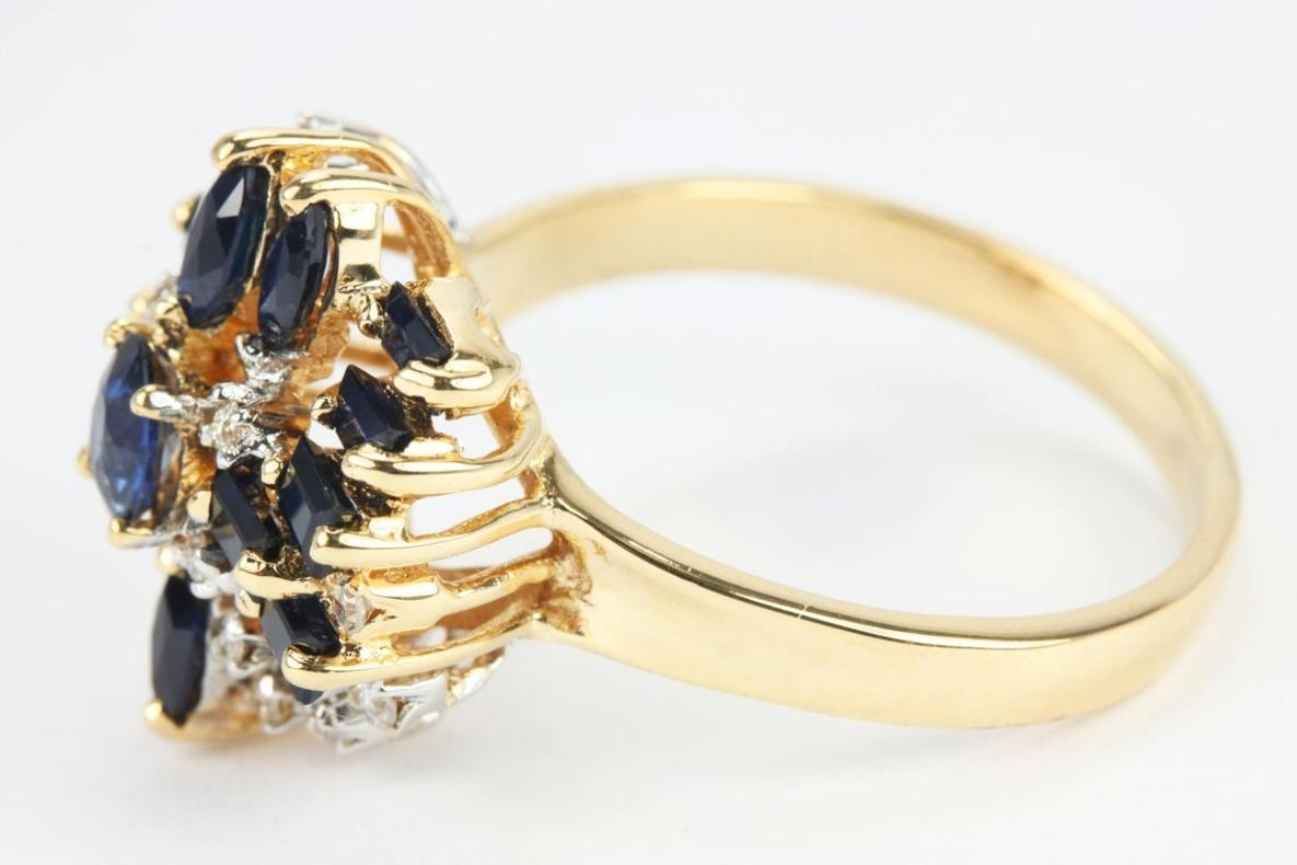 Displayed here is a vintage sapphire and diamond cocktail ring. It is quite a luxurious work of art and a true showstopper. High-quality sapphires make their way around the ring in numerous shapes. The center is a stunning oval sapphire followed by