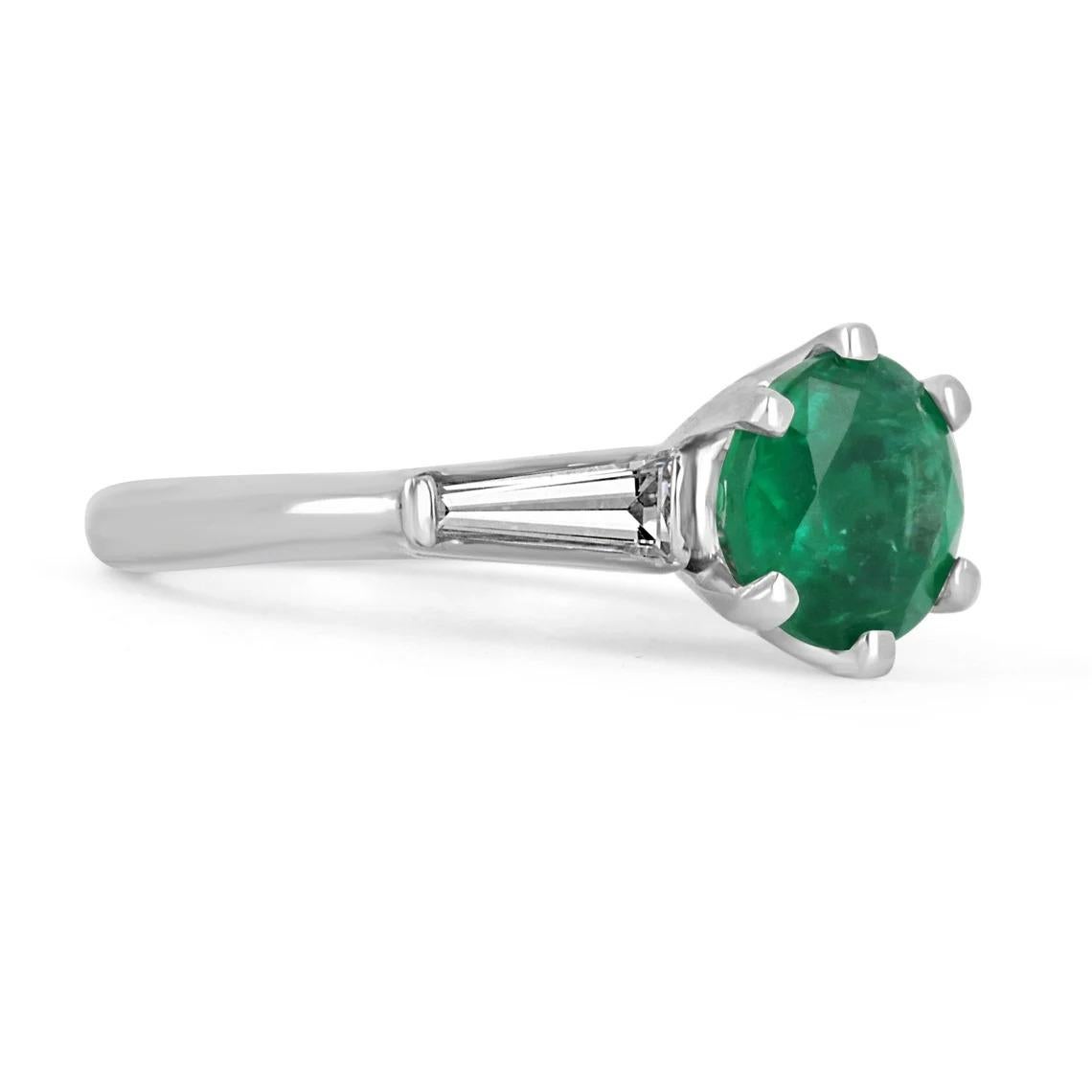 A classic among engagement rings, this genuine emerald, and tapered diamond engagement ring features a vibrant round Zambian emerald. The genuine rare gemstone has an incredible deep vivid-green color and very good eye clarity. The gem sits gently