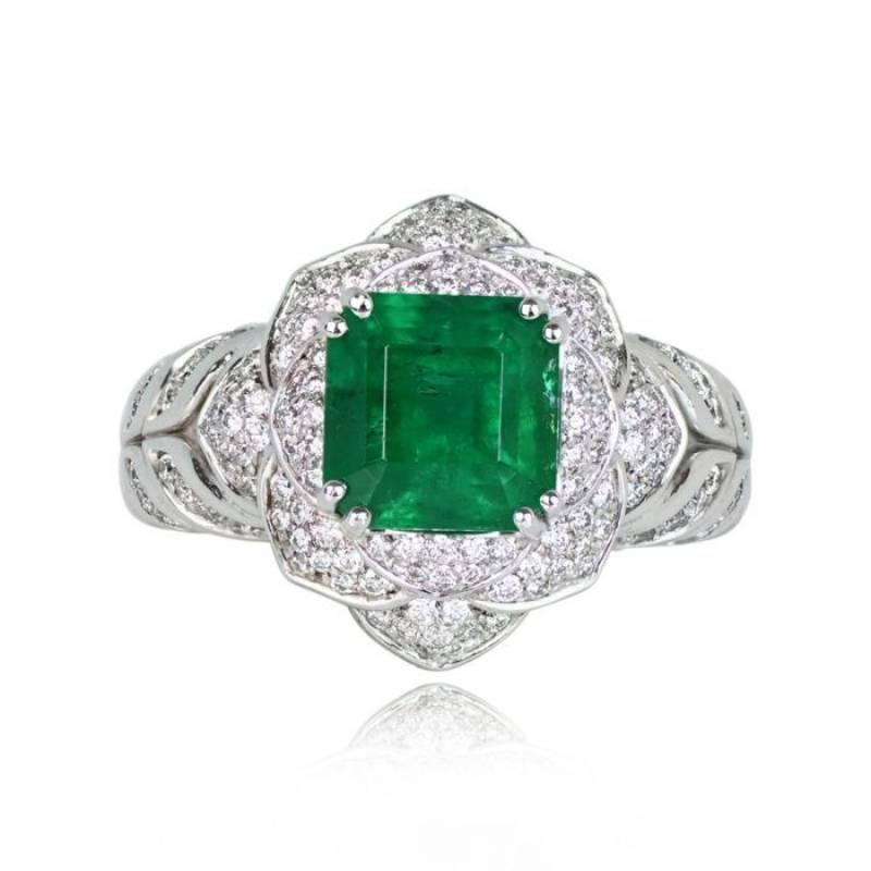 This exquisite gemstone ring showcases a 2.51-carat natural Zambian emerald, emerald-cut, and prong-set in 18k white gold. Round brilliant cut diamonds form a beautiful floral motif halo around the center stone. The ring's shoulders are adorned with