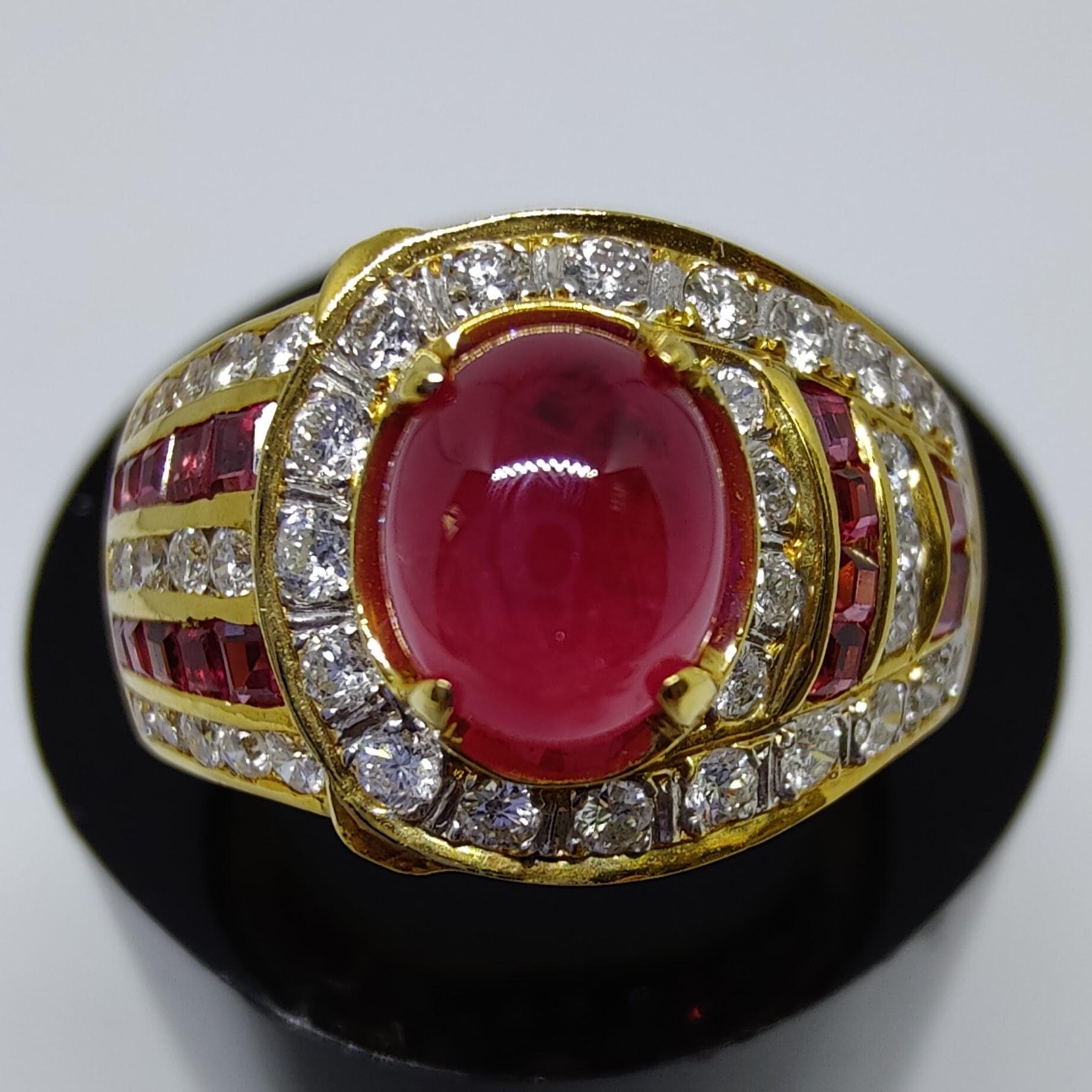 This magnificent vintage gold ring features a cabochon Ruby at the center, surrounded by paves of Blue Sapphire and Diamonds.

The vividly red oval cabochon cut Ruby weighs 2.52 carats, is accentuated by 0.4ct paves of 16 princess cut Ruby and