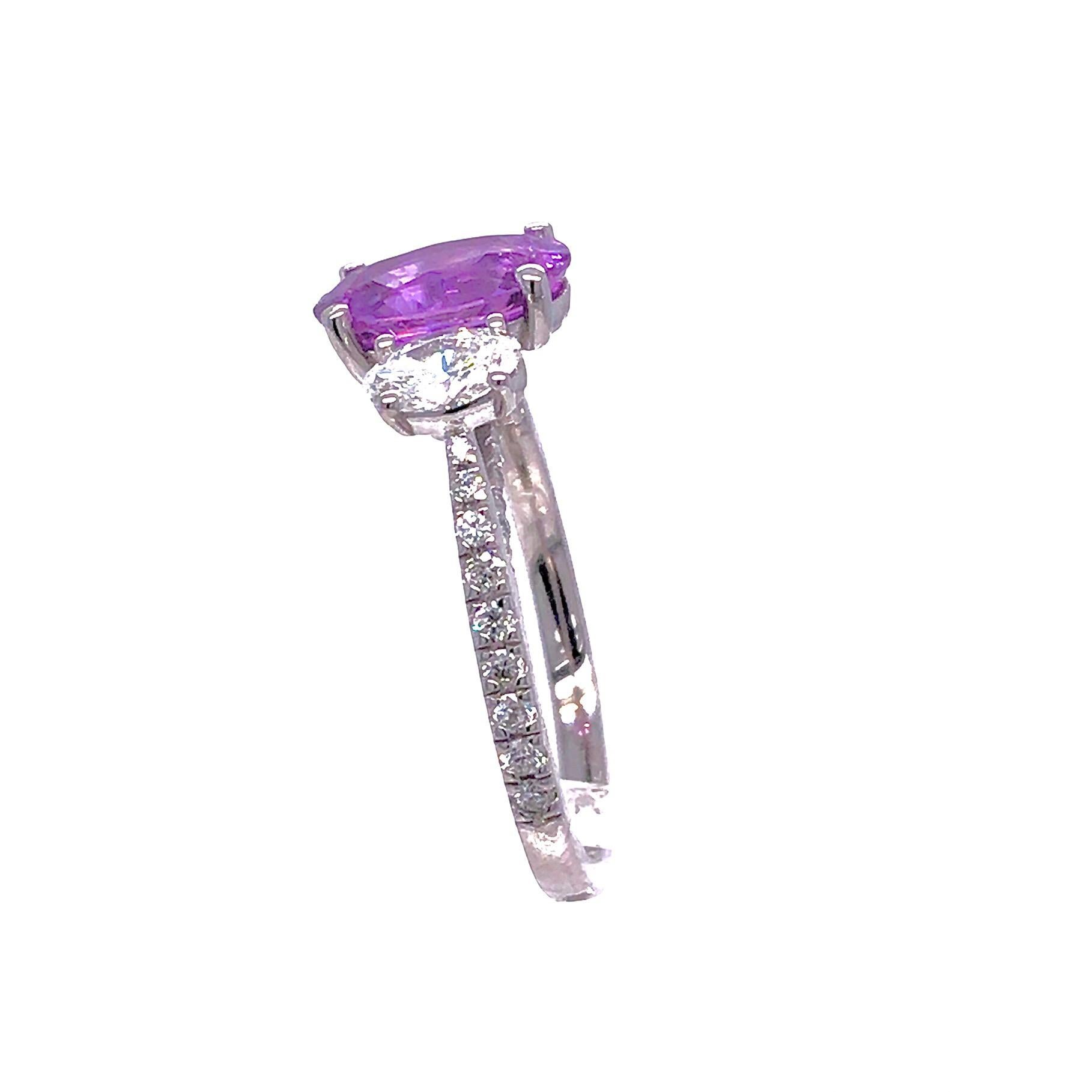 This ring has a center 2.53 carat Pink Rose sapphire, flanked by two oval cut diamonds at its face.
Additional diamonds decorate the side shank, as well as a bridge visible in the side view of the ring.
The total diamond weight is 1.02 carats.
Set