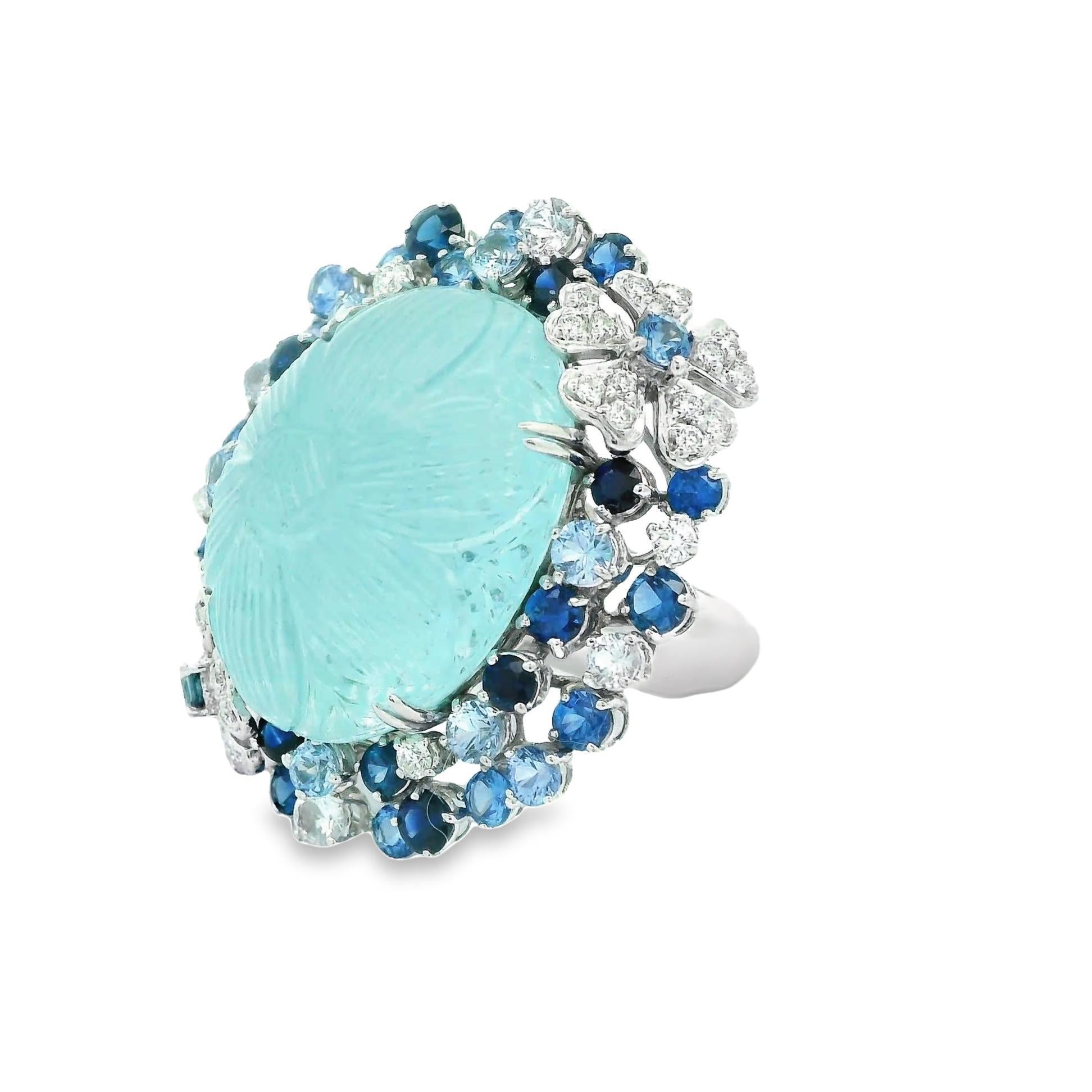 A beautiful and captivating cocktail ring, with an enchanting 25.33 carat hand-carved aquamarine. It has a bright sea-blue color and a lovely flower carving. Its smooth surface, carved with intricate petals, seems to dance with every glimmer of
