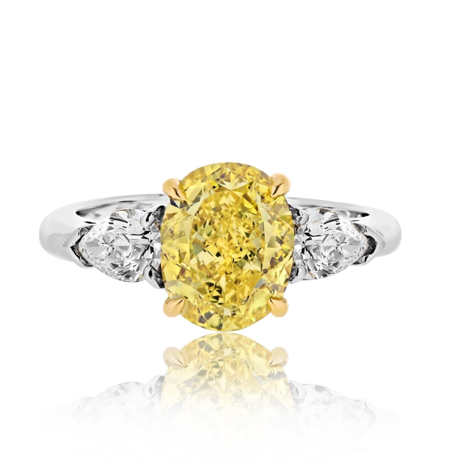 Embrace a vision of radiant elegance with this exquisite 2.53ct Fancy Vivid Yellow Oval Cut Three Stone Diamond Engagement Ring. 

The centerpiece, a resplendent 2.53ct oval cut diamond, captivates with its Fancy Vivid Yellow hue, held in place with