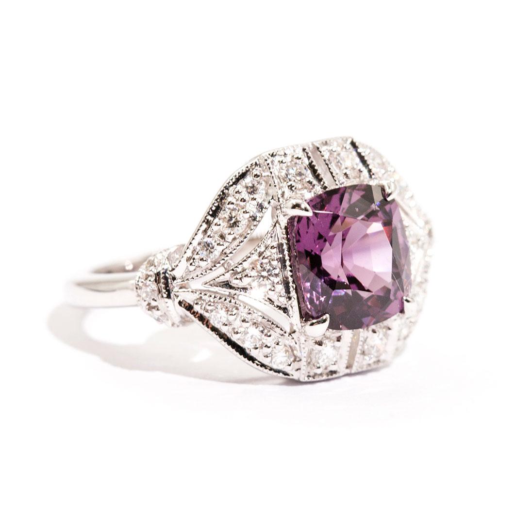 Forged in 18 carat white gold is this art deco inspired ring that features a gorgeous 2.54 carat bright pinkish purple cushion cut natural spinel complimented by a total of 0.45 carats of sparkling round brilliant cut diamonds. We have named this