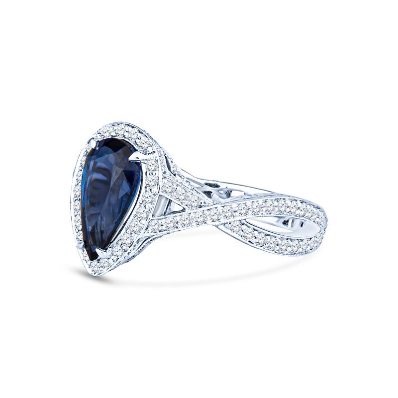This exquisite ring features a captivating 2.54 carat pear shaped natural blue sapphire, complemented by a double crisscrossing shank and diamond halo with a total carat weight of 0.75 carats. Set in luxurious platinum, this piece is a perfect