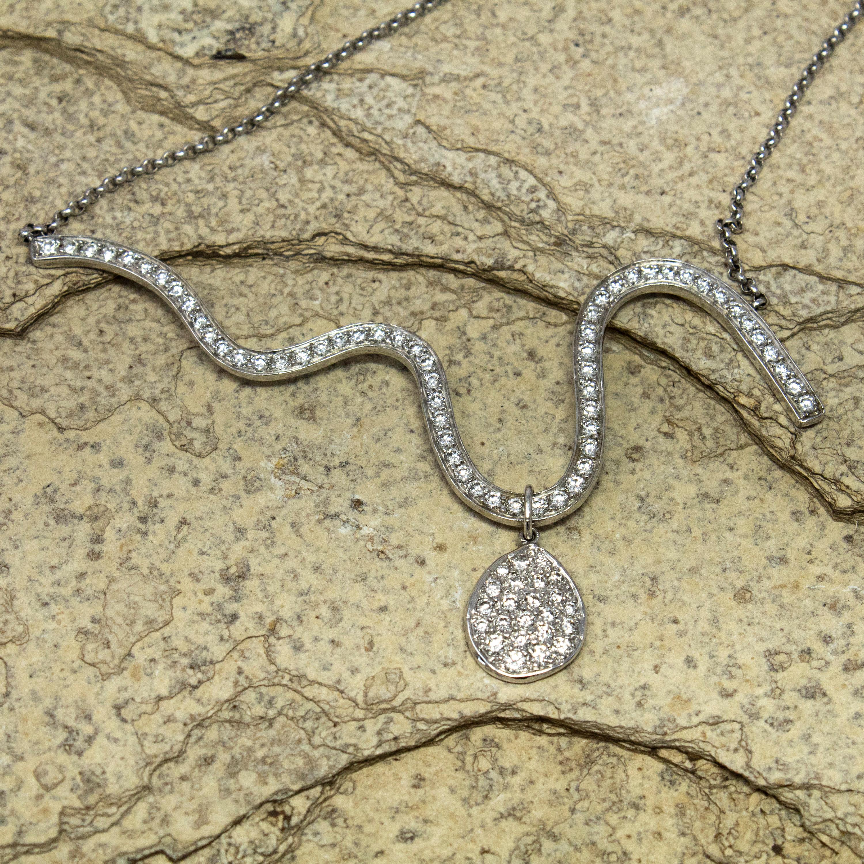  This elegant diamond wave necklace invokes the beauty of a calming ocean day. Beautiful diamonds play across the perfectly executed piece of jewelry. As a bonus, the diamond pave drop can be removed and worn on a separate chain. This 18kt and